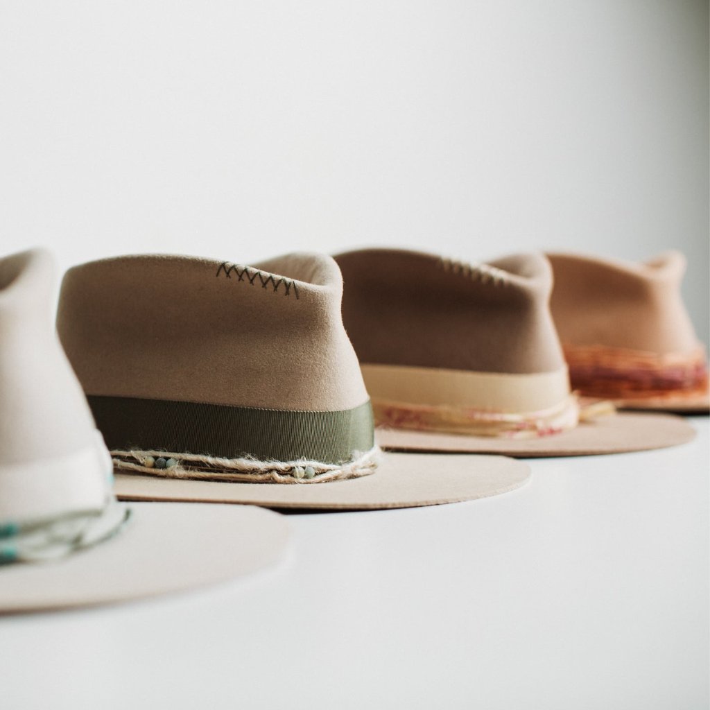 A row of handcrafted felt hats from the Strickland Collection by PHYLLi Designs, showcasing natural tones and artisan trims
