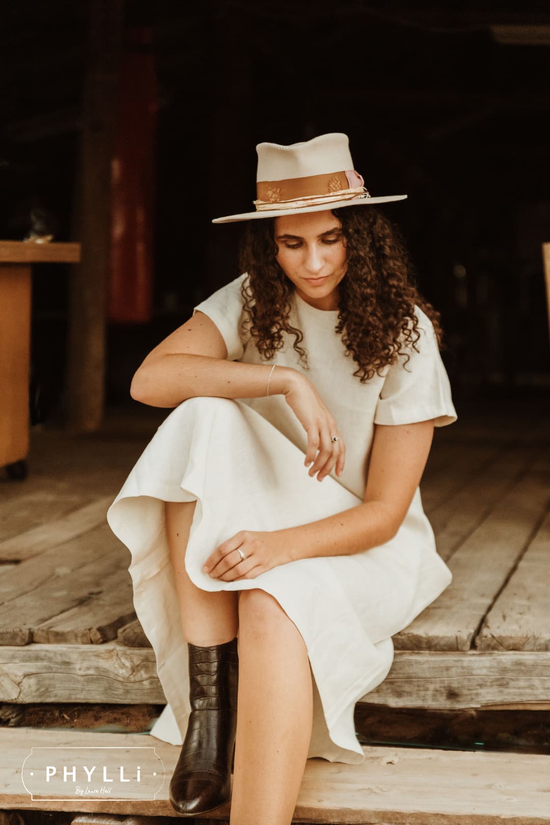 Sarah Wheeler wearing the Malibu beige felt hat by PHYLLi Designs with copper band and feather detail.