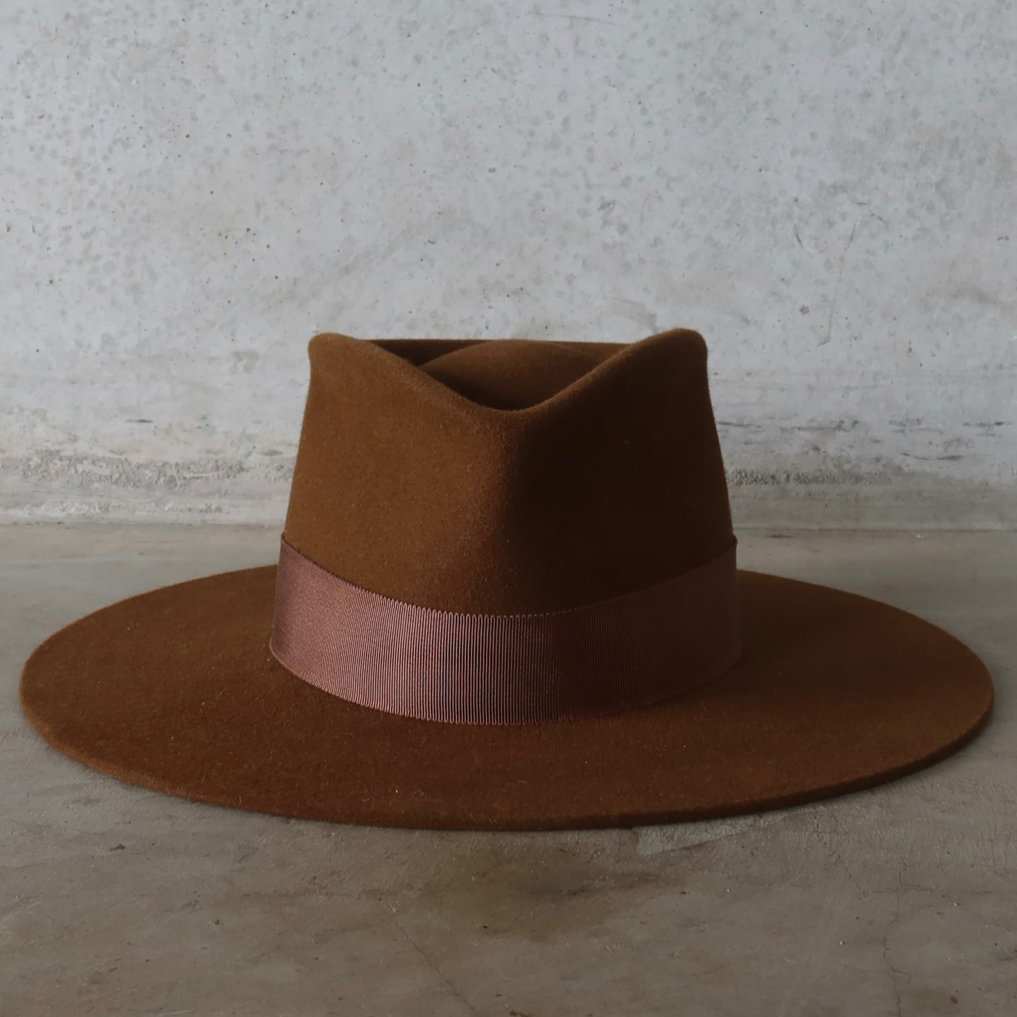 Brown felt hat with a wide brim on a textured surface