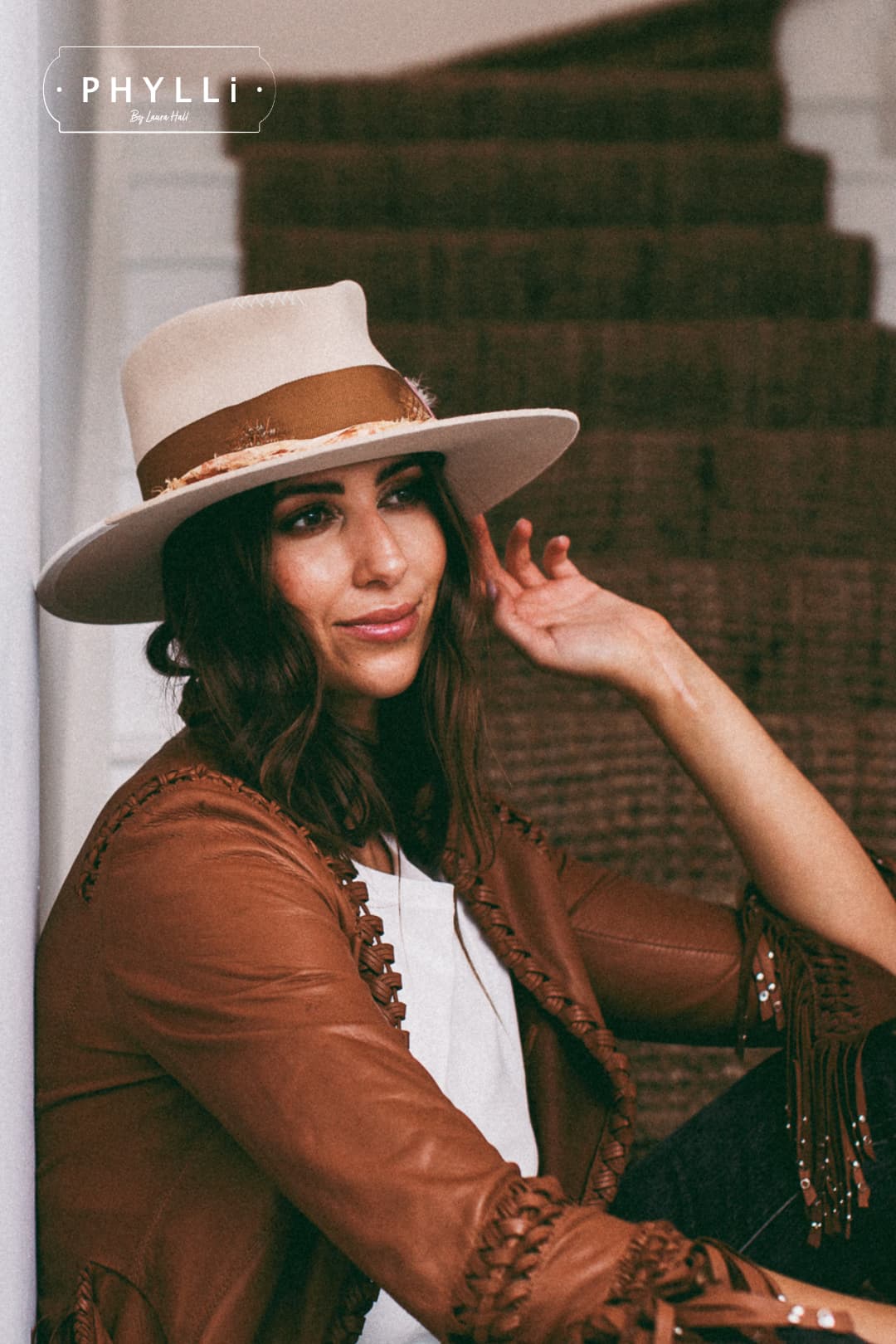 Woman wearing the Malibu beige felt hat by PHYLLi Designs styled with a leather jacket.