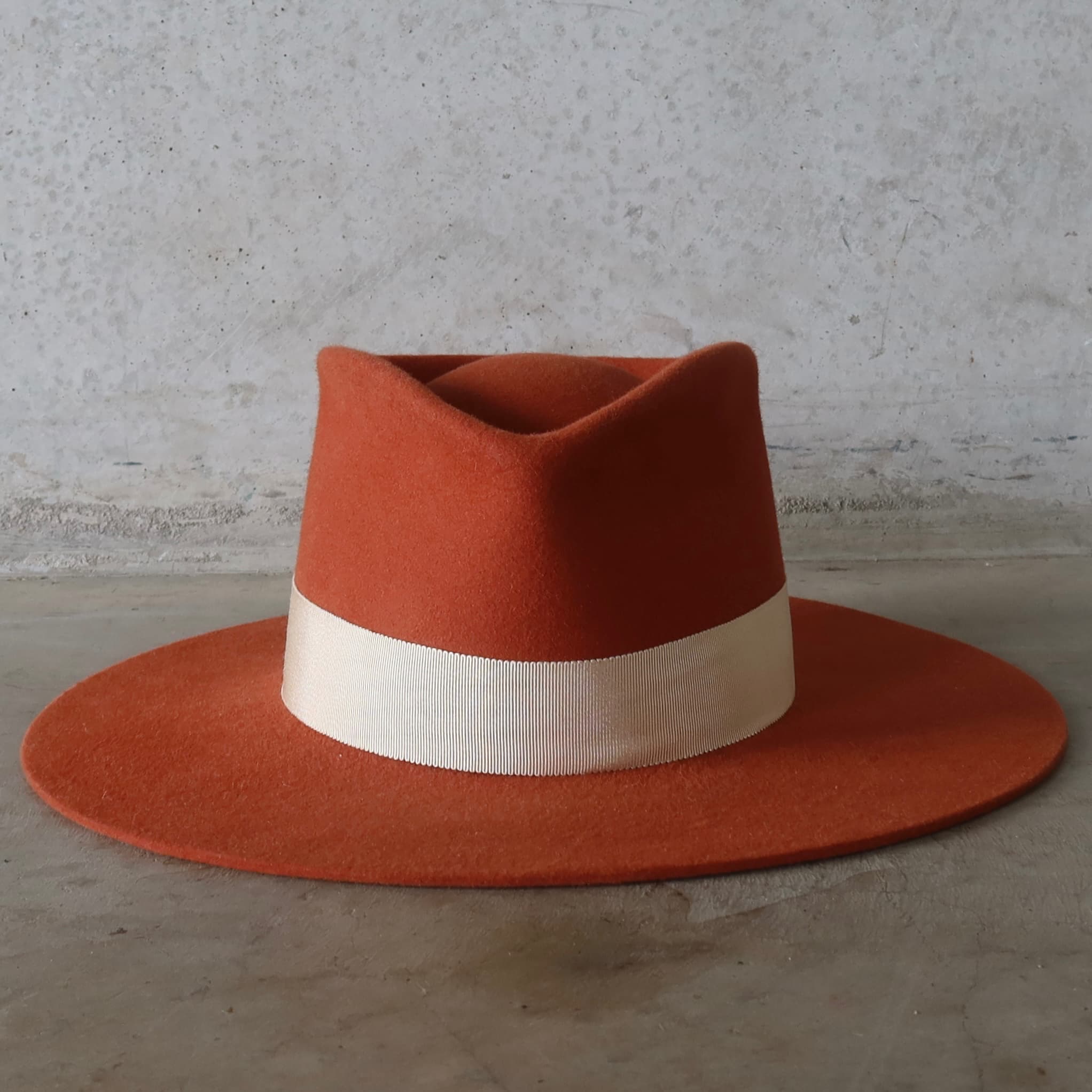 Orange hat with a sand band on a grey surface