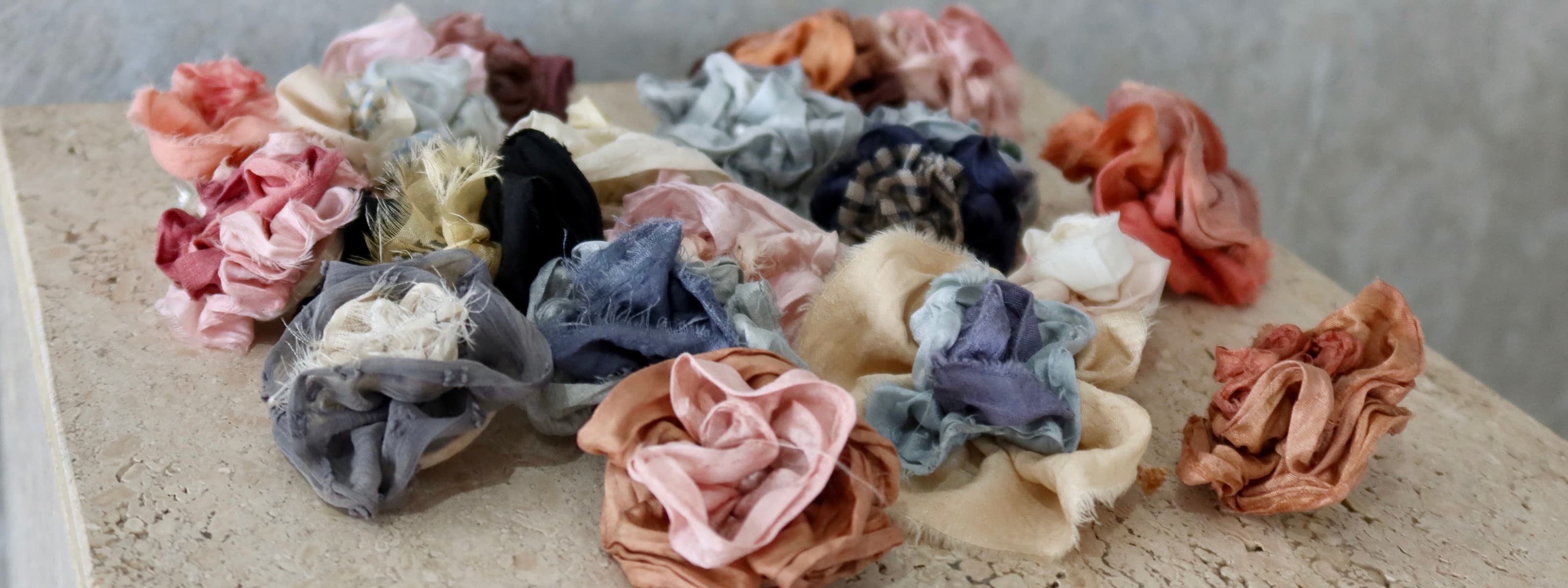 Collection of colorful fabric flowers on a neutral background