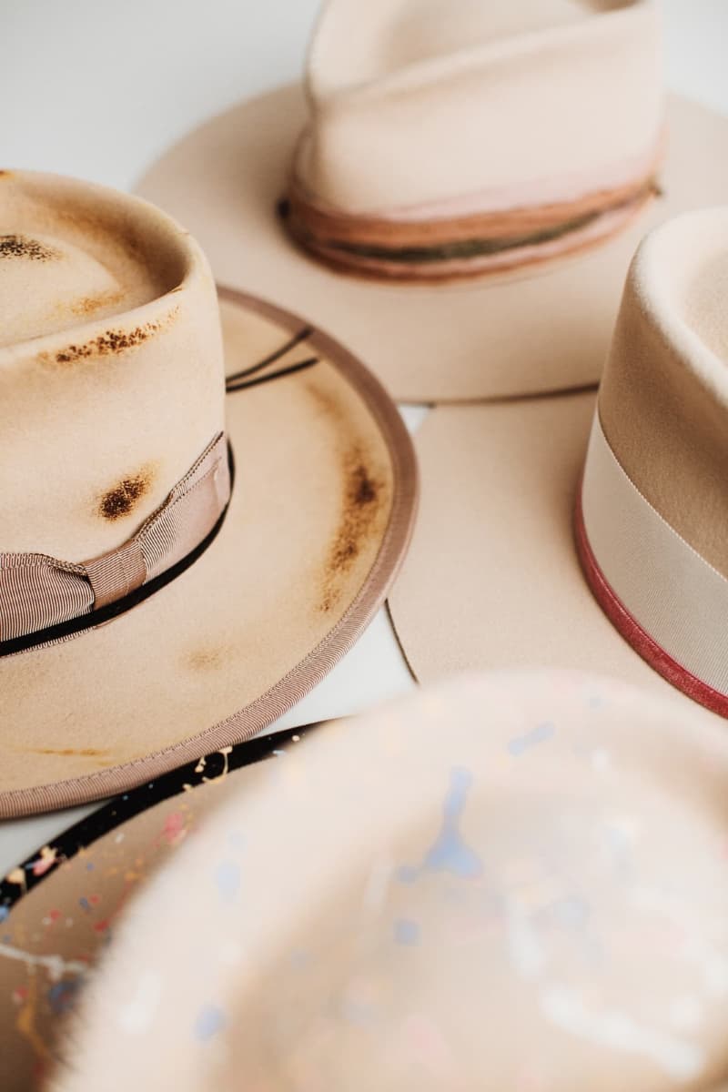 Collection of beige hats with decorative bands on a light background