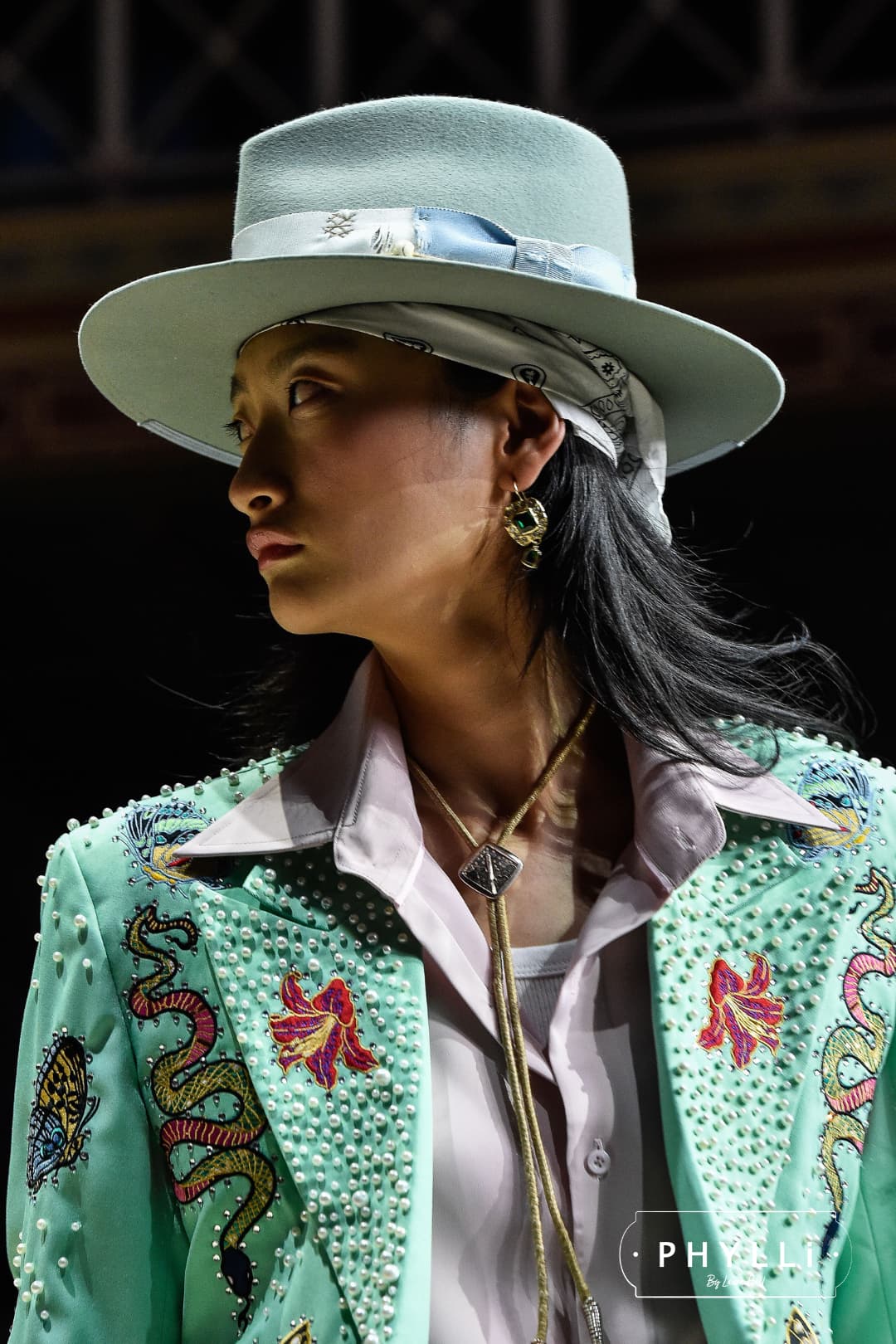 Woman wearing the Accra sage felt hat by PHYLLi Designs with cornflower bow and ivory grosgrain ribbon band in runway portrait setting.
