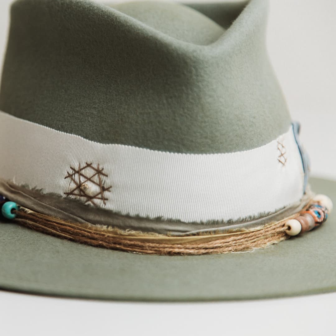 Close up detail of the Accra felt hat showing hand-painted recycled glass bead cluster made in Ghana.