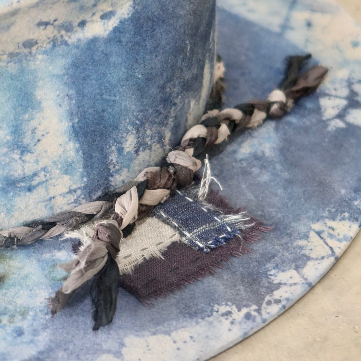 Close up detail of the Aizome Limited Edition felt hat showing plaited sari silk trimming.