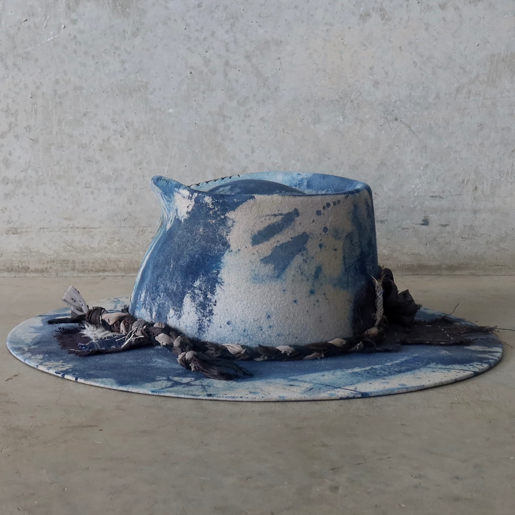 Back left angle of the dove grey indigo tie dye felt hat Aizome Limited Edition by PHYLLi Designs with plaited sari silk trim and patchwork detail.