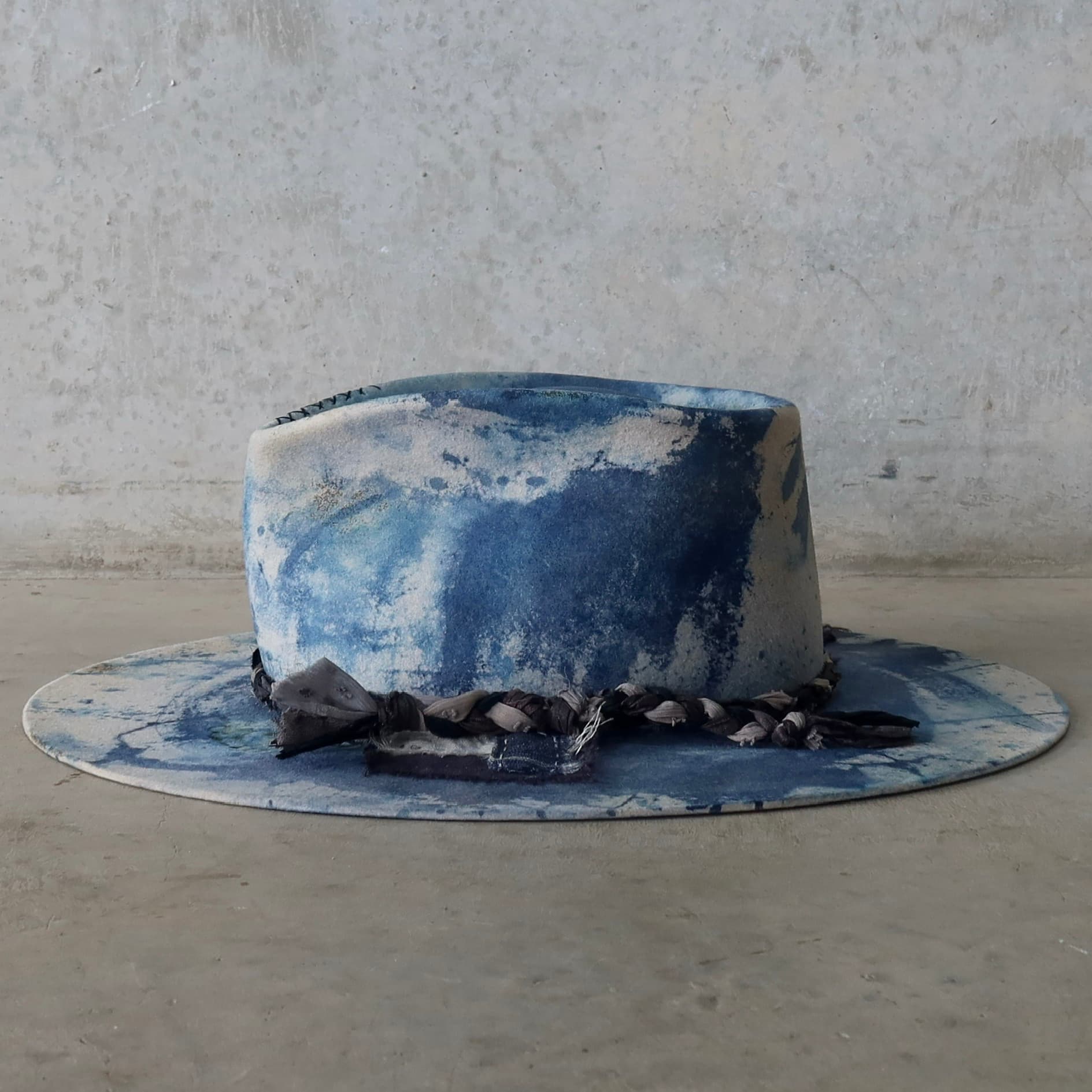 Left side view of the dove grey indigo tie dye felt hat Aizome Limited Edition by PHYLLi Designs with plaited sari silk trim and wabi sabi linen patch.