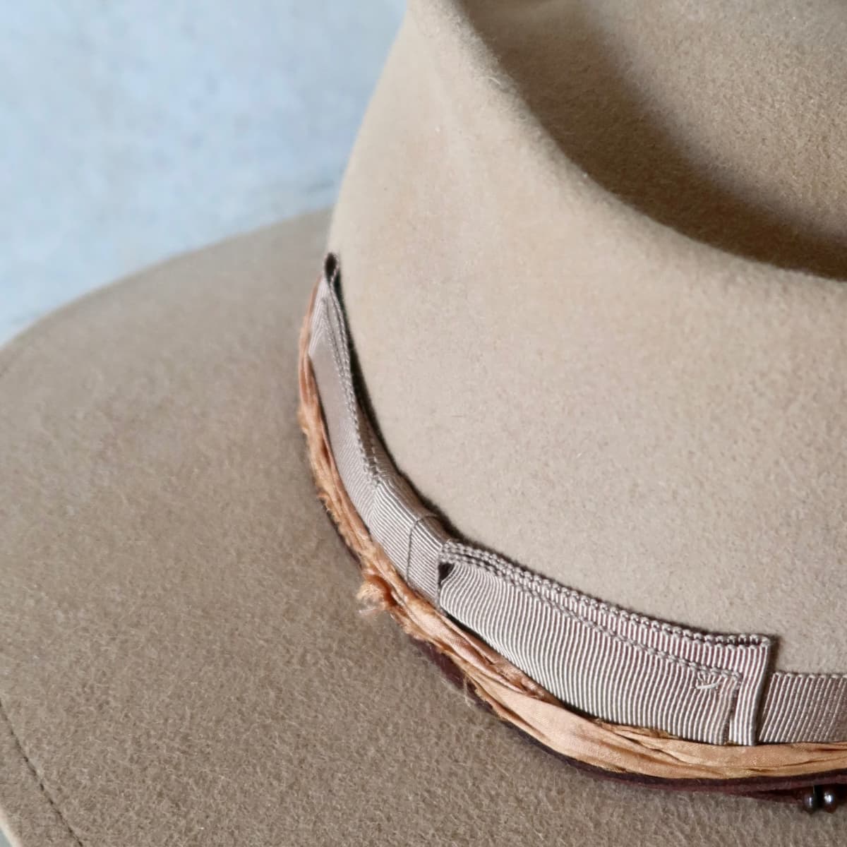 Close up detail of the Alexander felt hat showing taupe Japanese grosgrain double bow band and layered copper sari silk trim.