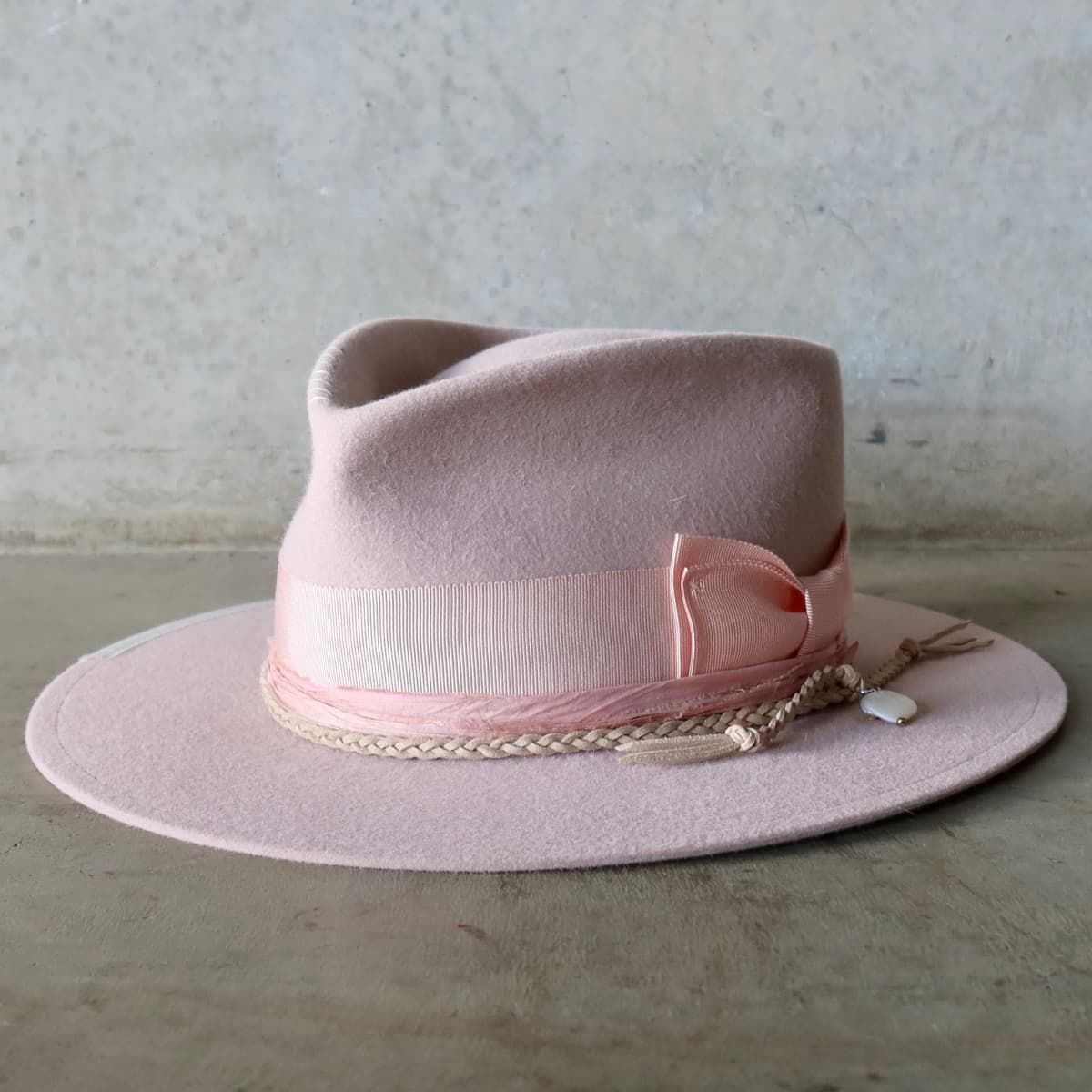 Front left angle of the baby pink felt hat Argyle Limited Edition by PHYLLi Designs with sherbet pink grosgrain bow band and sari silk trim.