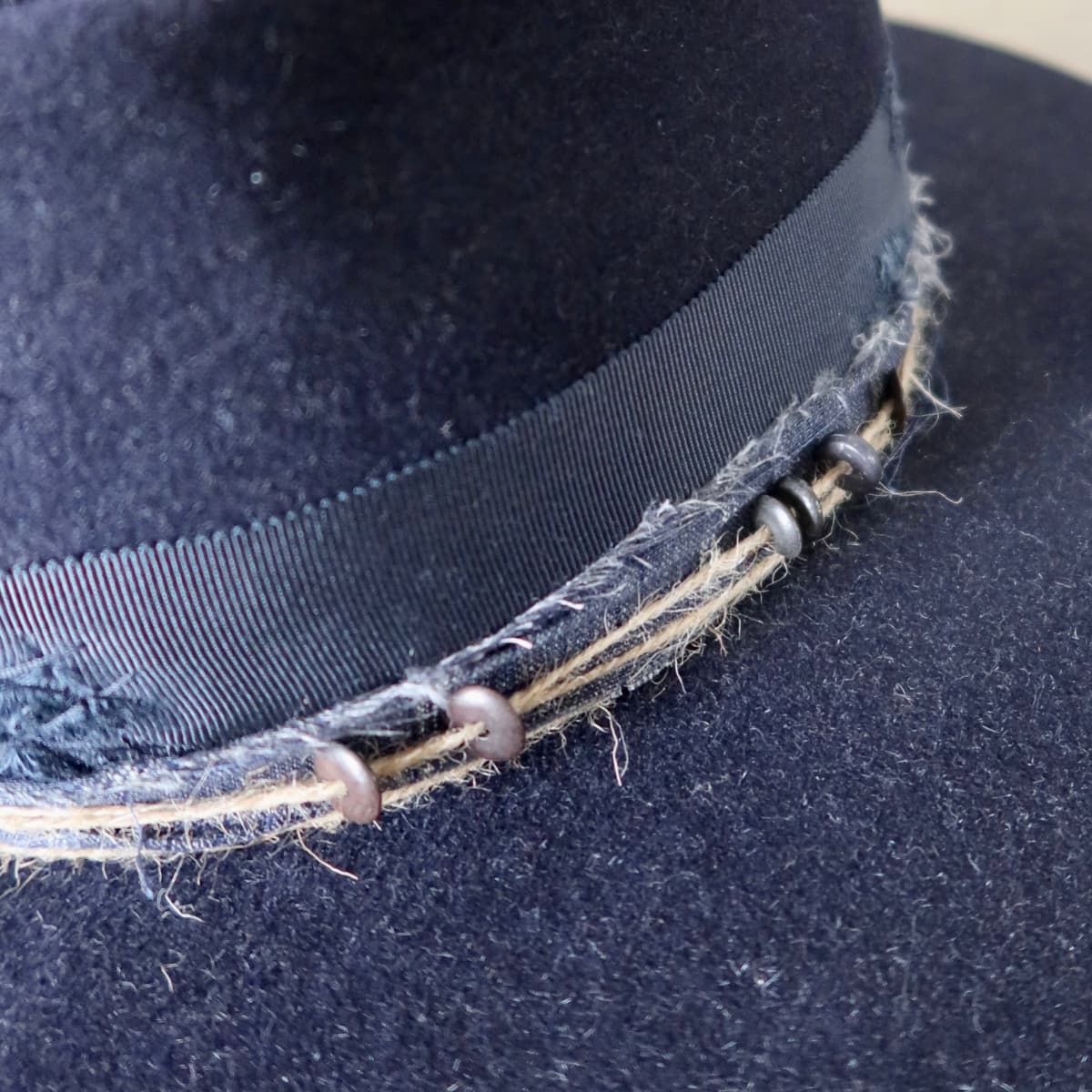 Close up detail of the Armadale felt hat showing pinstripe cotton trim with twine wraps and bone bead detailing.