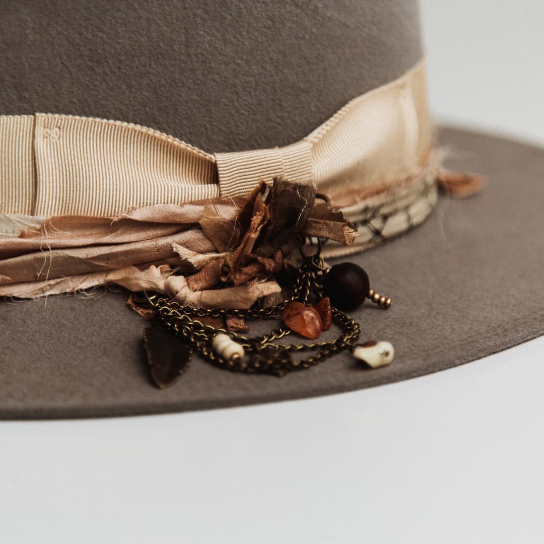 Close up detail of the Arrowtown felt hat showing bronze chunky hat pin with sari silks, tassel, charms and beads.