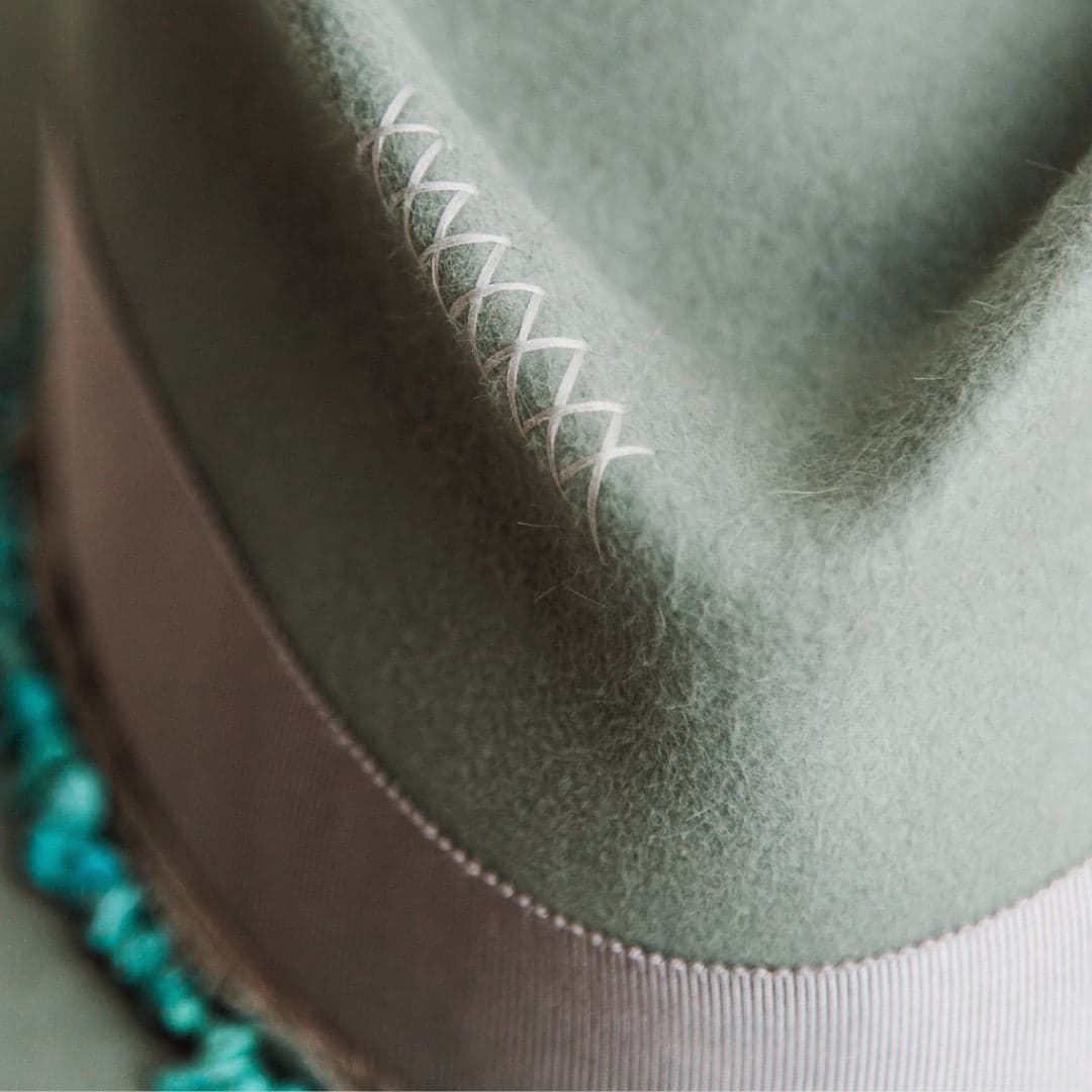 Close up detail of the Aurora felt hat showing hand-stitched cross detailing in dove on the sage felt crown.