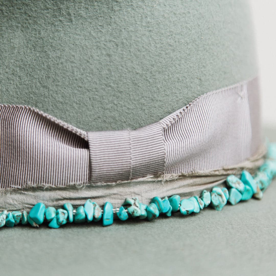 Close up detail of the Aurora felt hat showing turquoise stone hat necklace and steel grey sari silk trimming.