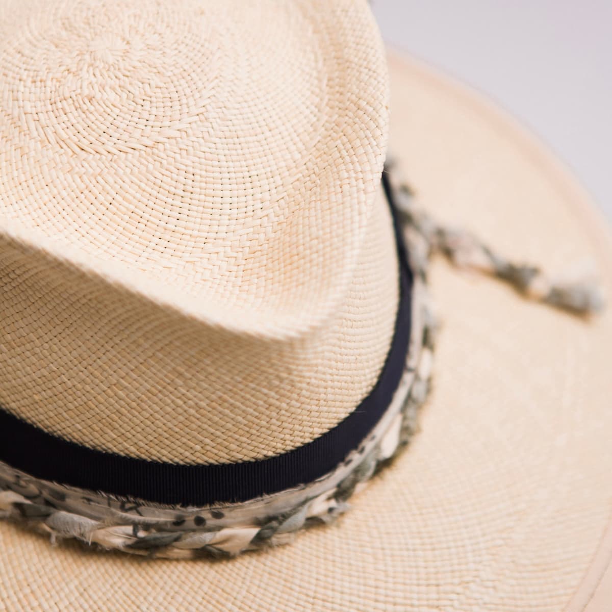 Close up detail of the Blue Jean Panama hat showing handwoven toquilla straw crown with dark navy Japanese grosgrain band and plaited sari silk trim in ivory, olive and teal.