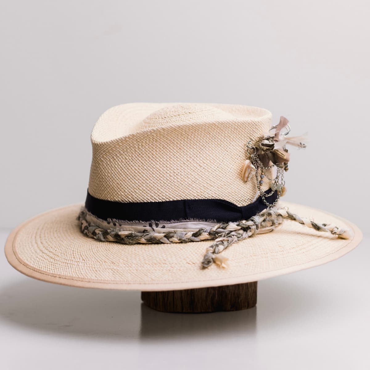 Front left angle of the Blue Jean Natural Panama hat by PHYLLi Designs with dark navy Japanese grosgrain bow band and plaited sari silk trim in ivory, olive and teal.