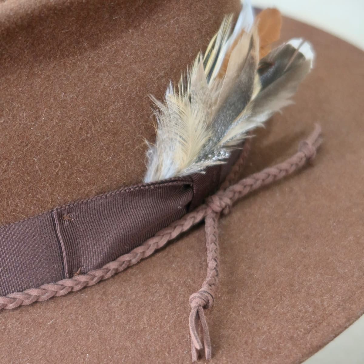 Close up detail of the Botero felt hat showing fallen feather bunch with dark brown Japanese grosgrain band.
