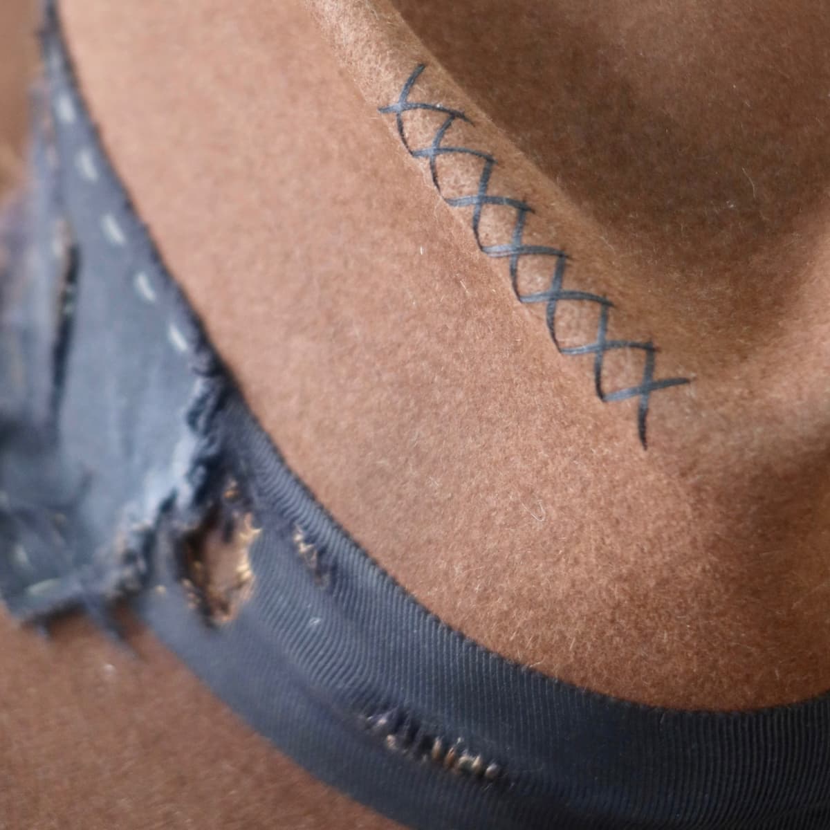 Close up detail of the Brenner Limited Edition felt hat showing hand-stitched cross detail in black.