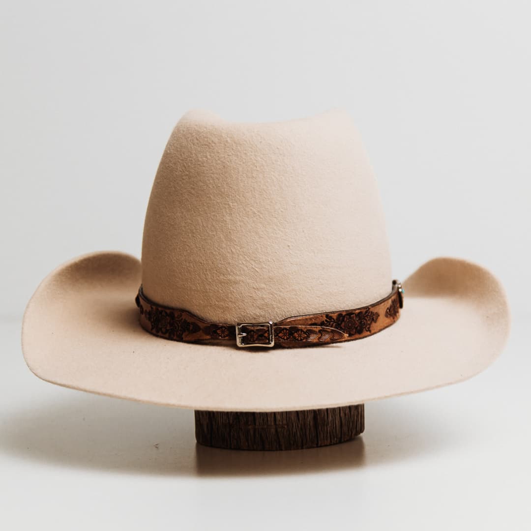 Back view of the Phylli x Buffalo Girl Rugged Desert Hat Band Western Floral featuring antique brown leather hat band fastened with western style buckle on a beige felt hat by PHYLLi Designs.