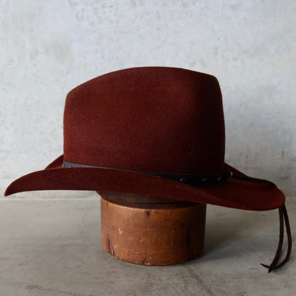 Left side view of the Russet felt cowboy hat Burgundy by PHYLLi Designs with gunmetal studded leather hat band.