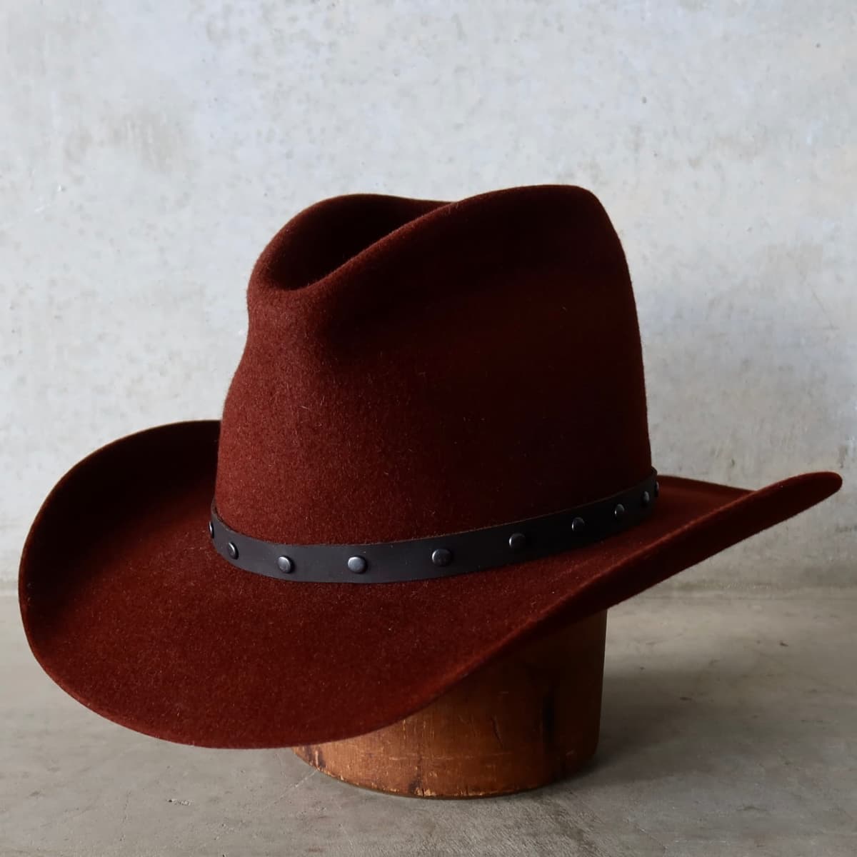 Front left angle of the Russet felt cowboy hat Burgundy by PHYLLi Designs with gunmetal studded dark brown leather hat band.