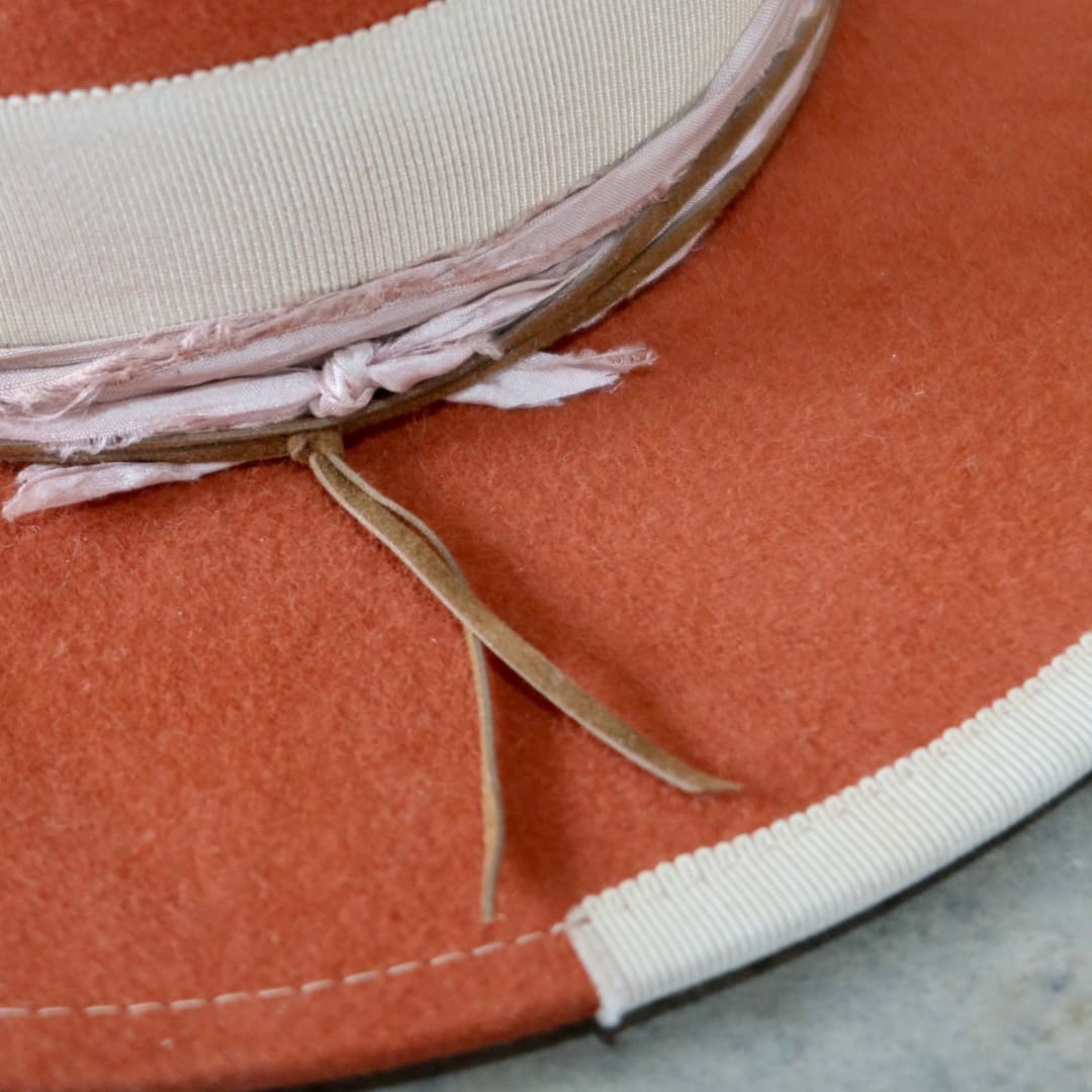 Close up detail of the Canna felt hat showing the pink sari silk brim trim and tan suede string.