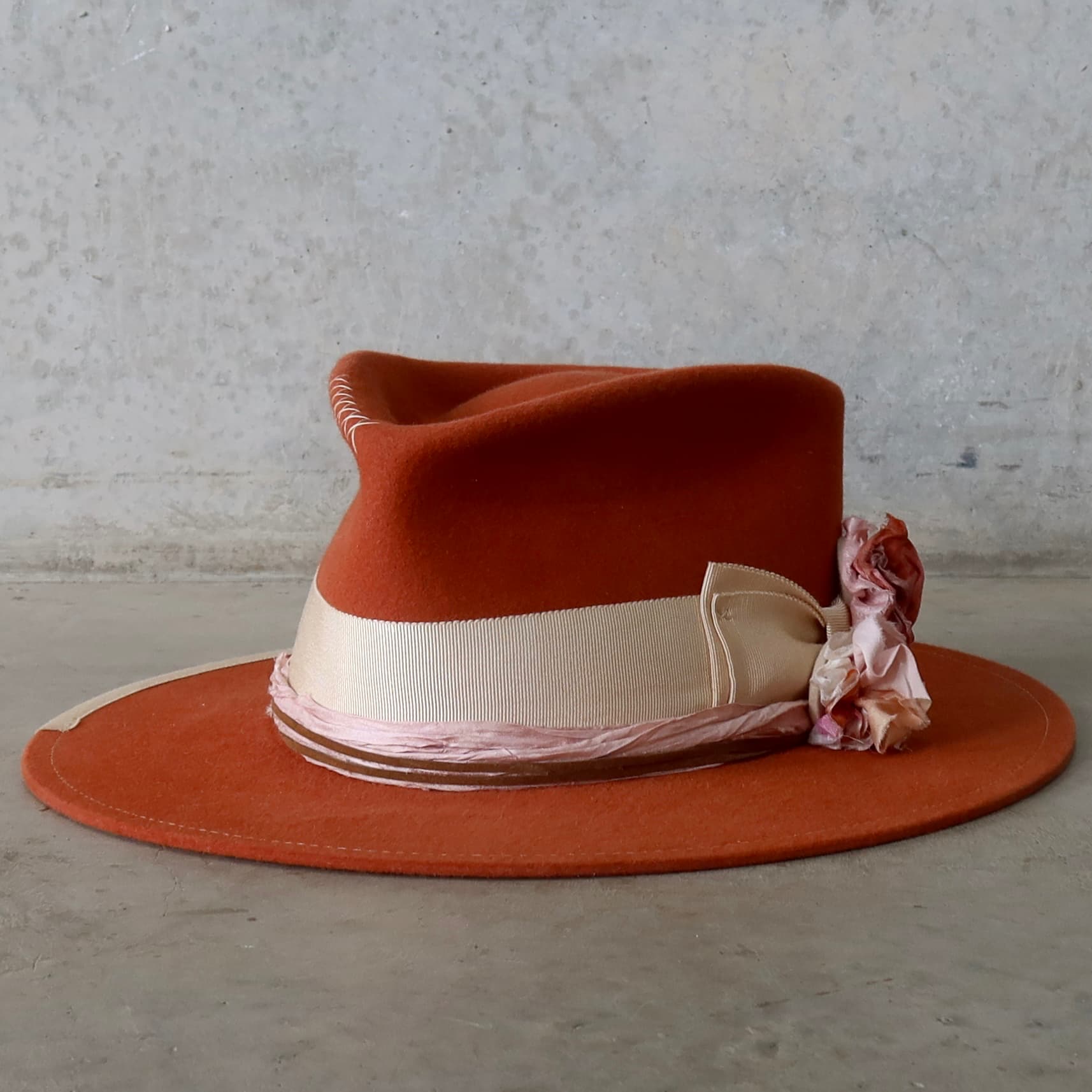 Front left angle of the Spiced Pumpkin felt hat Canna by PHYLLi Designs with sand grosgrain bow band and pink sari silk blooms.