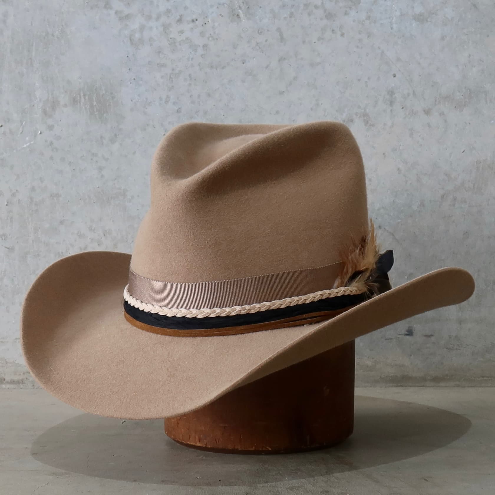 Front left angle of the camel felt cowboy hat Casey by PHYLLi Designs featuring plaited nude suede string and tan suede tie detail.