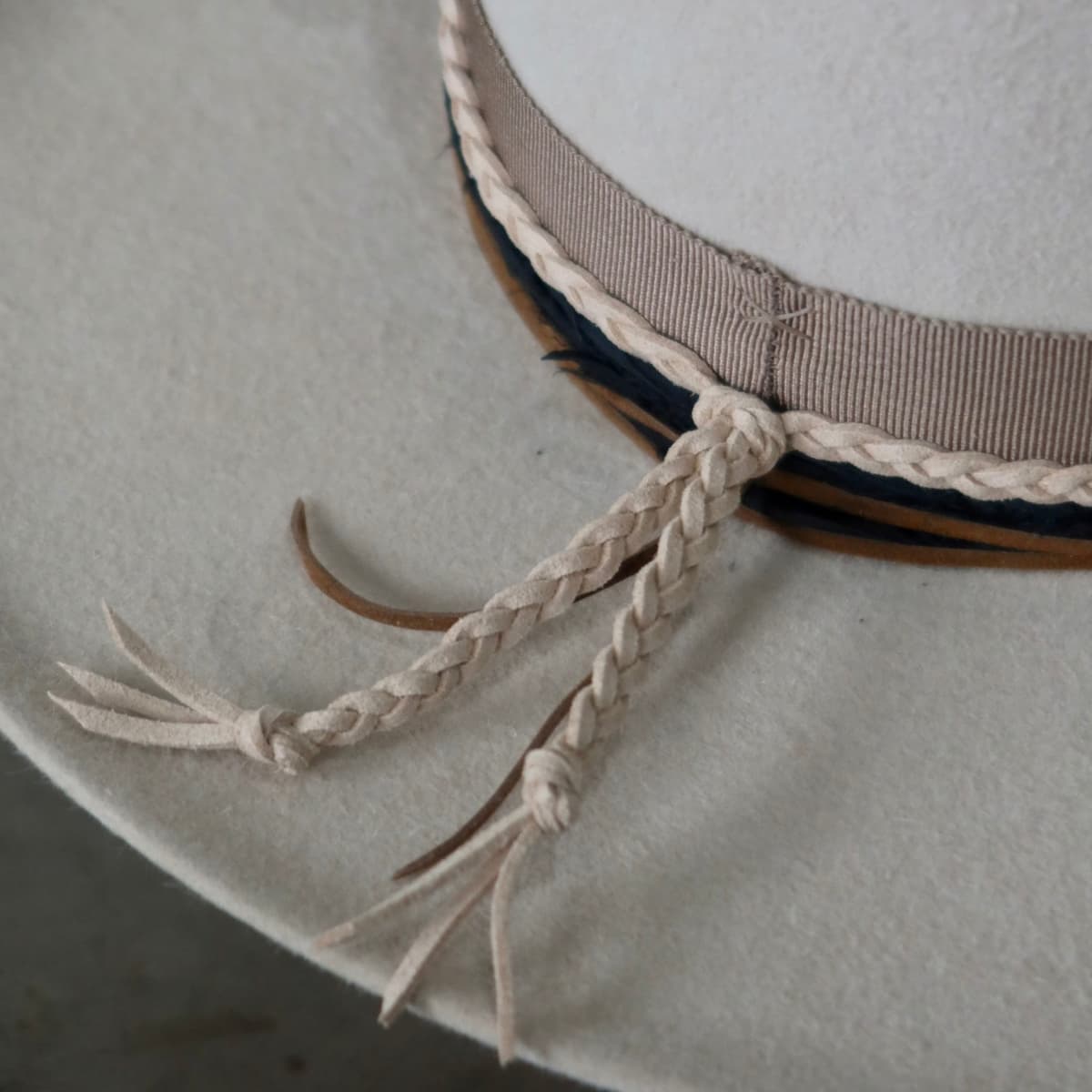 Close up detail of the Casey Beige cowboy hat showing plaited nude suede tie with tan suede string wrap tied at the back.