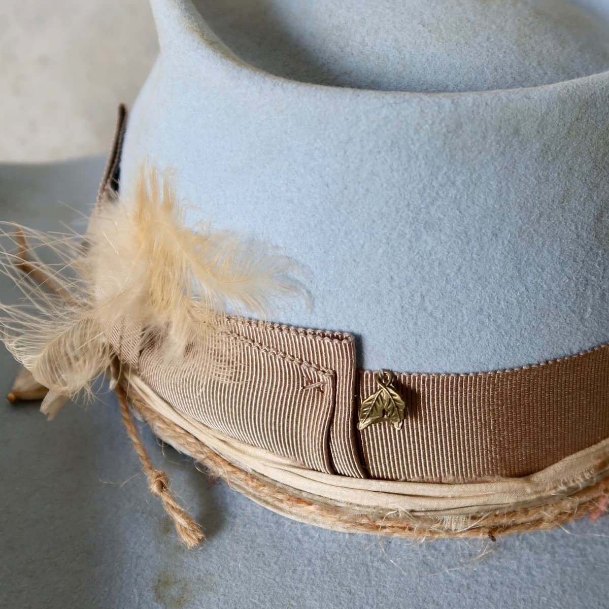 Close up detail of the Clareville Limited Edition felt cowboy hat showing taupe Japanese grosgrain double bow band with pearl and bronze leaf charm.