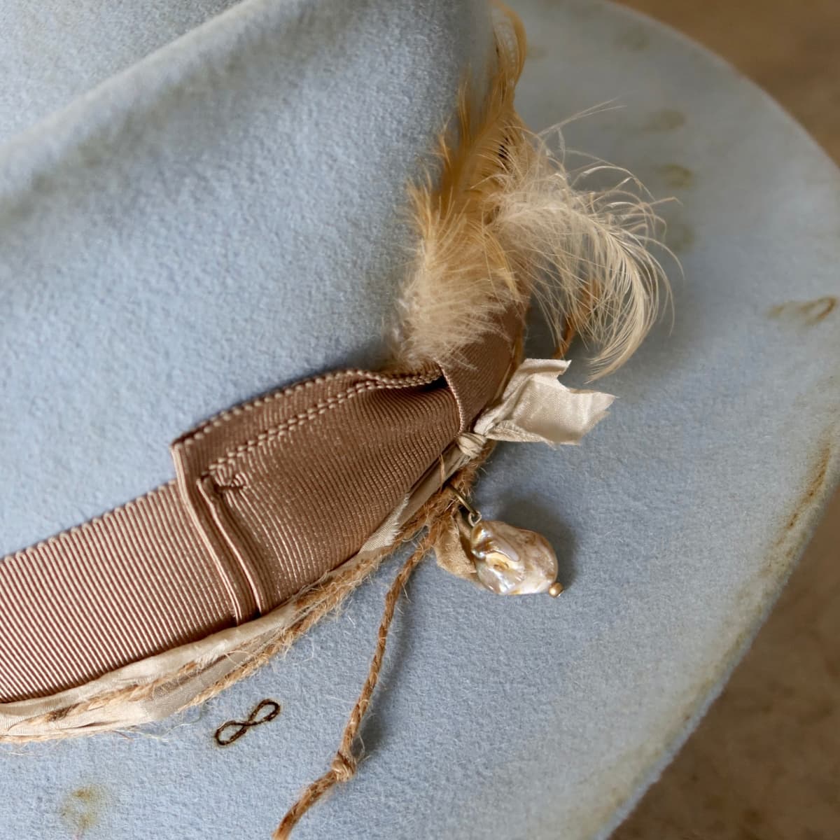 Close up detail of the Clareville Limited Edition felt cowboy hat showing feather trim and pearl charm detail.