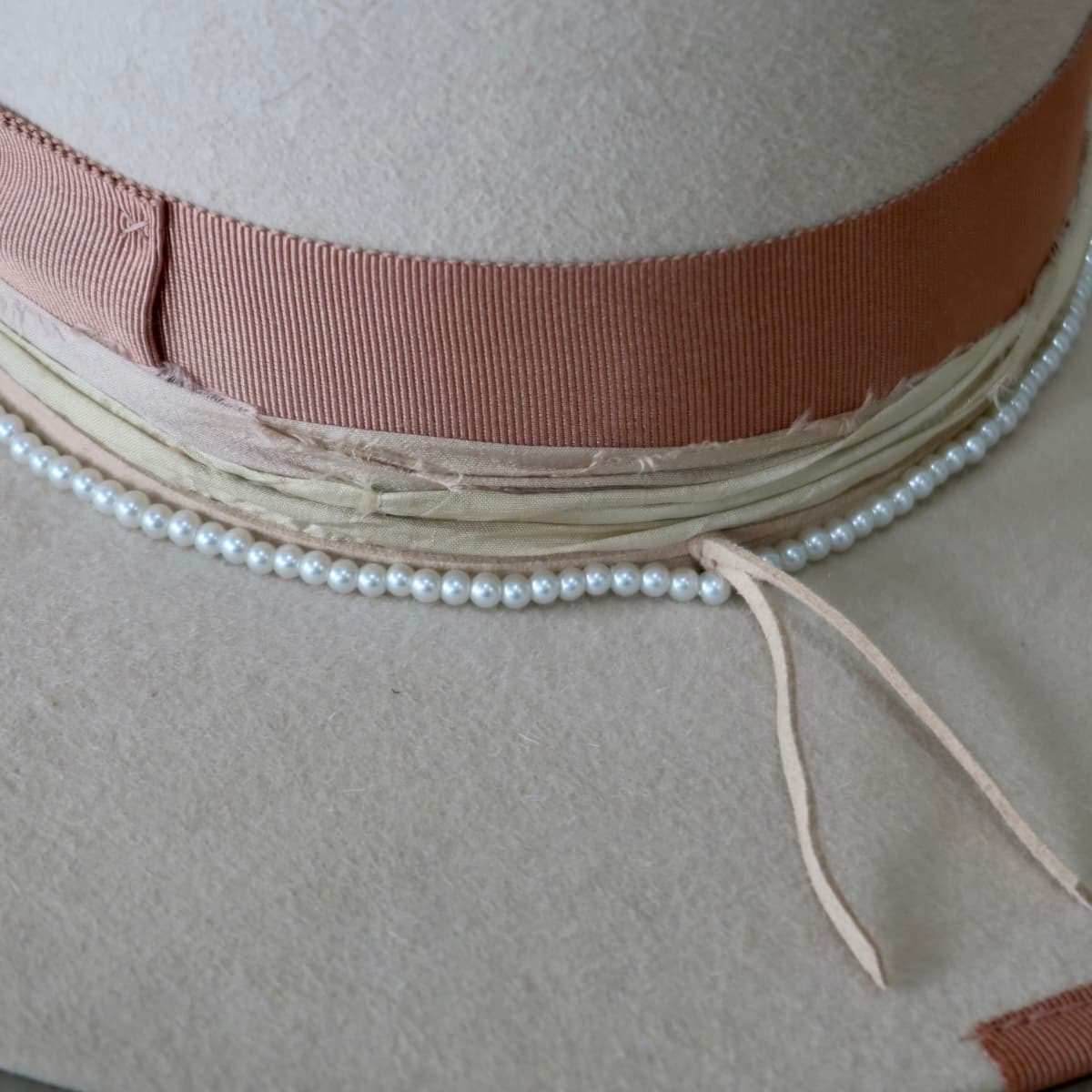 Close up detail of the Clementine felt hat showing glass pearl hat necklace and sorbet sari silk trim.
