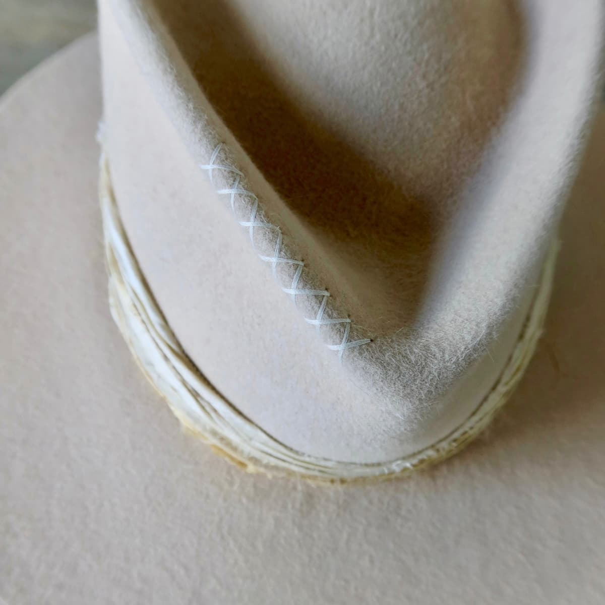 Close up detail of the Coastline felt hat showing ivory hand-stitched cross detail on the crown.