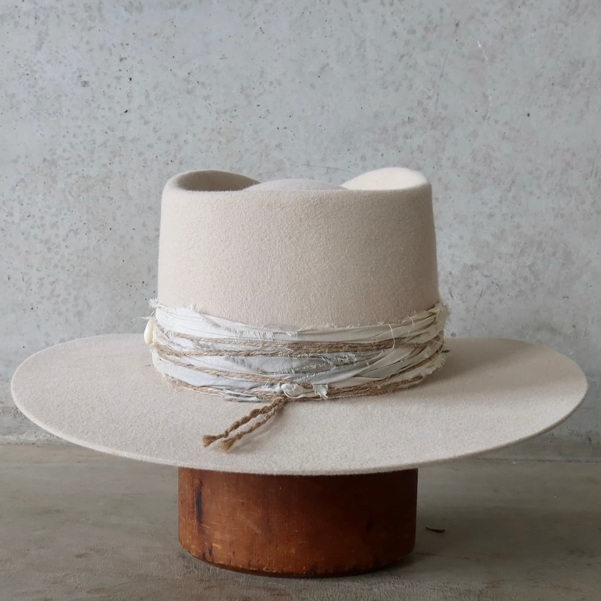 Back view of the beige felt hat Coastline by PHYLLi Designs featuring layered sari silk trims and twine wraps.