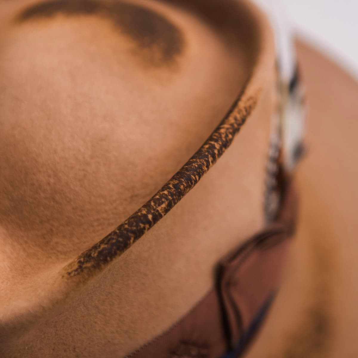 Close up detail of the Columbian camel felt hat showing hand-burnt felt patina finishing along the crown edge.