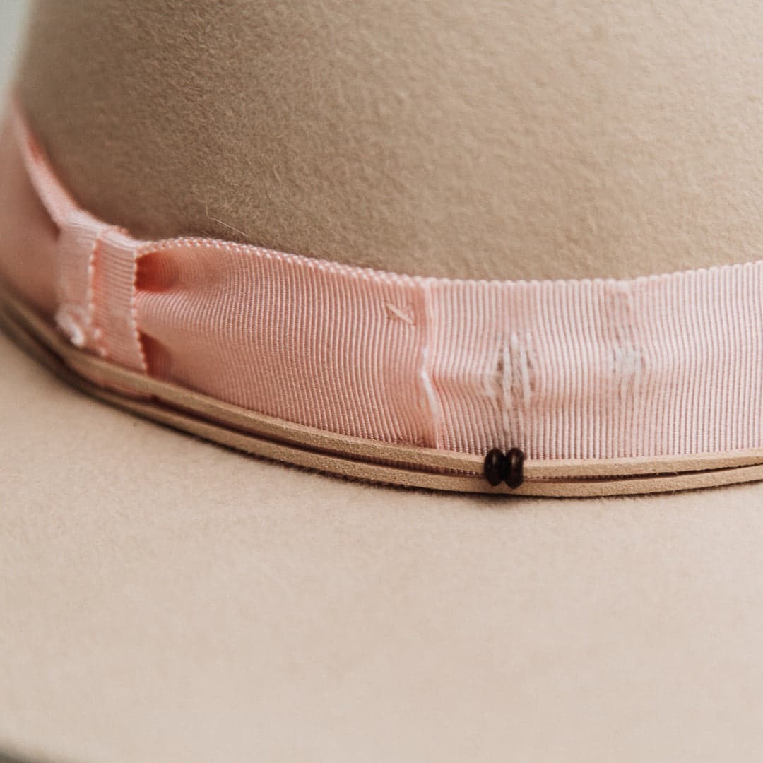 Close up detail of the Curlewis felt hat showing nude suede string trim with wooden bead detail and ivory hand stitching.