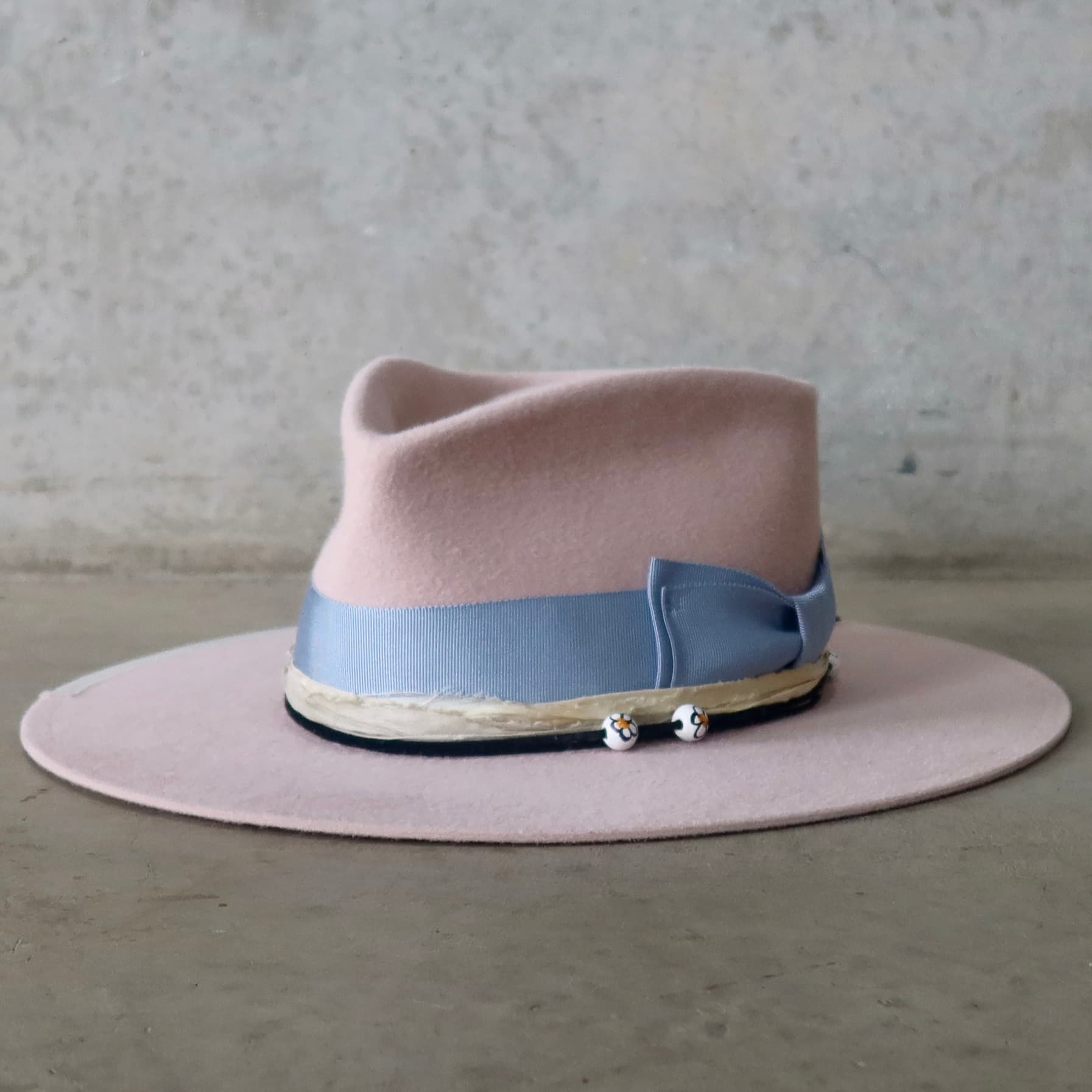 Front left angle of the baby pink felt hat Daisy by PHYLLi Designs with cornflower grosgrain bow and sorbet sari silk trim.