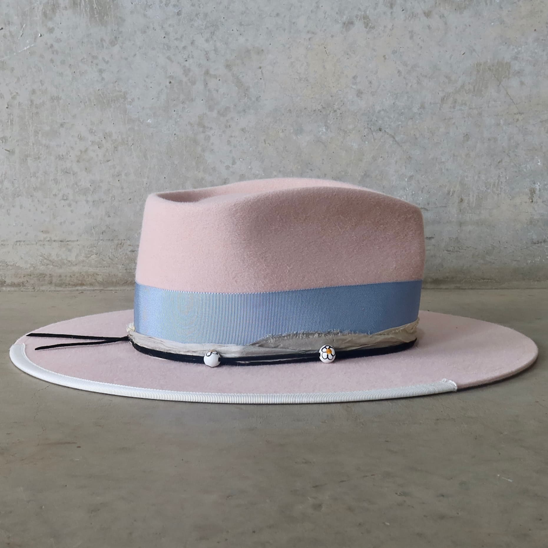 Right side view of the baby pink felt hat Daisy by PHYLLi Designs with cornflower Japanese grosgrain bow band and ivory brim trim.