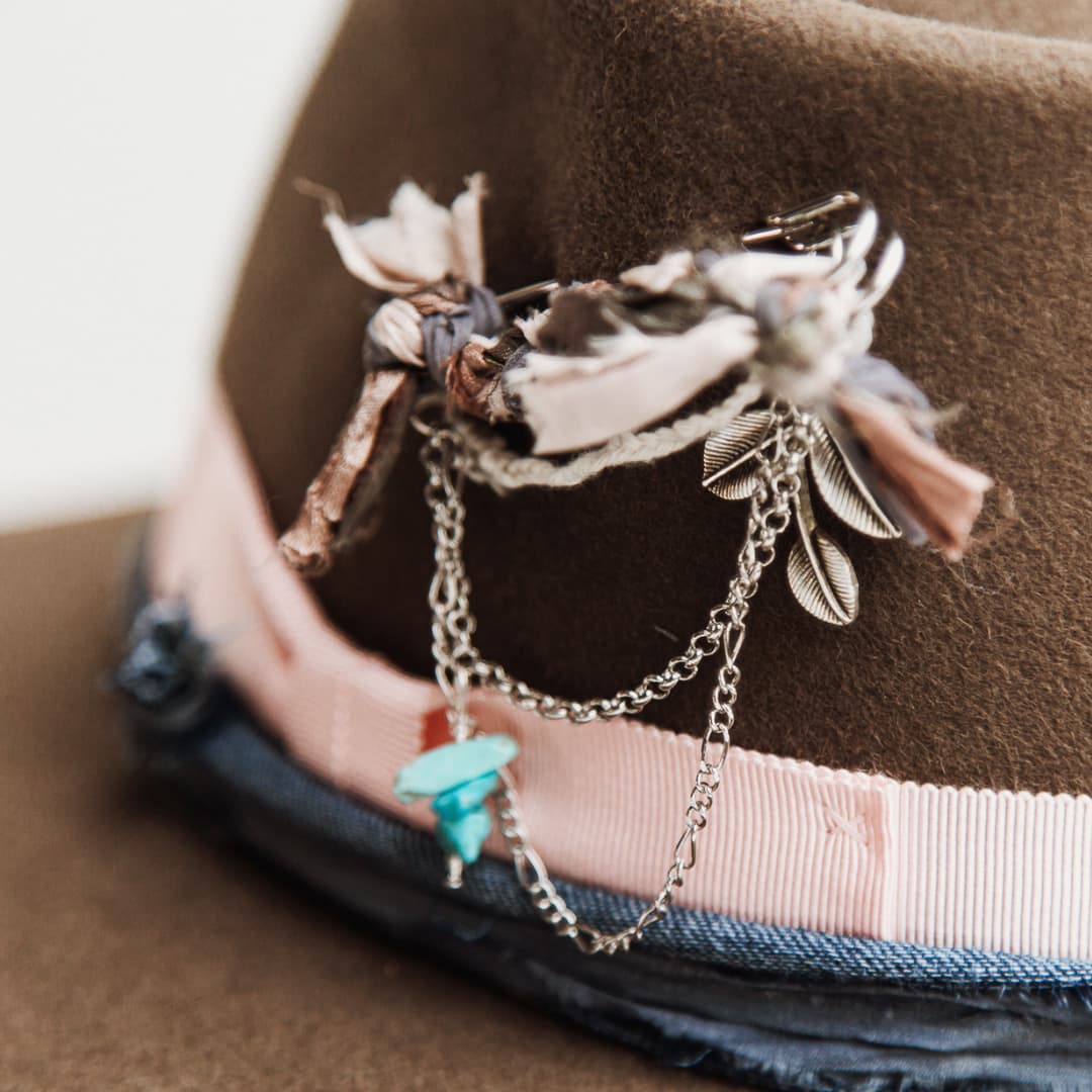 Close up detail of the Denman felt hat showing silver chunky hat pin with charms and turquoise beading.