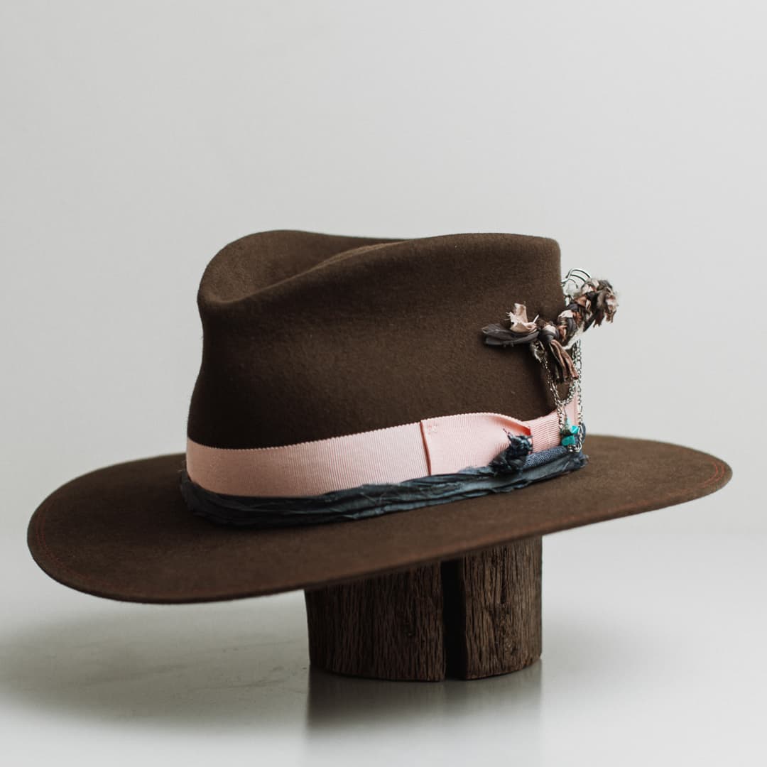 Front left angle of the Denman dirty olive felt hat by PHYLLi Designs with sherbet pink grosgrain band, denim sari silk trim and silver hat pin.