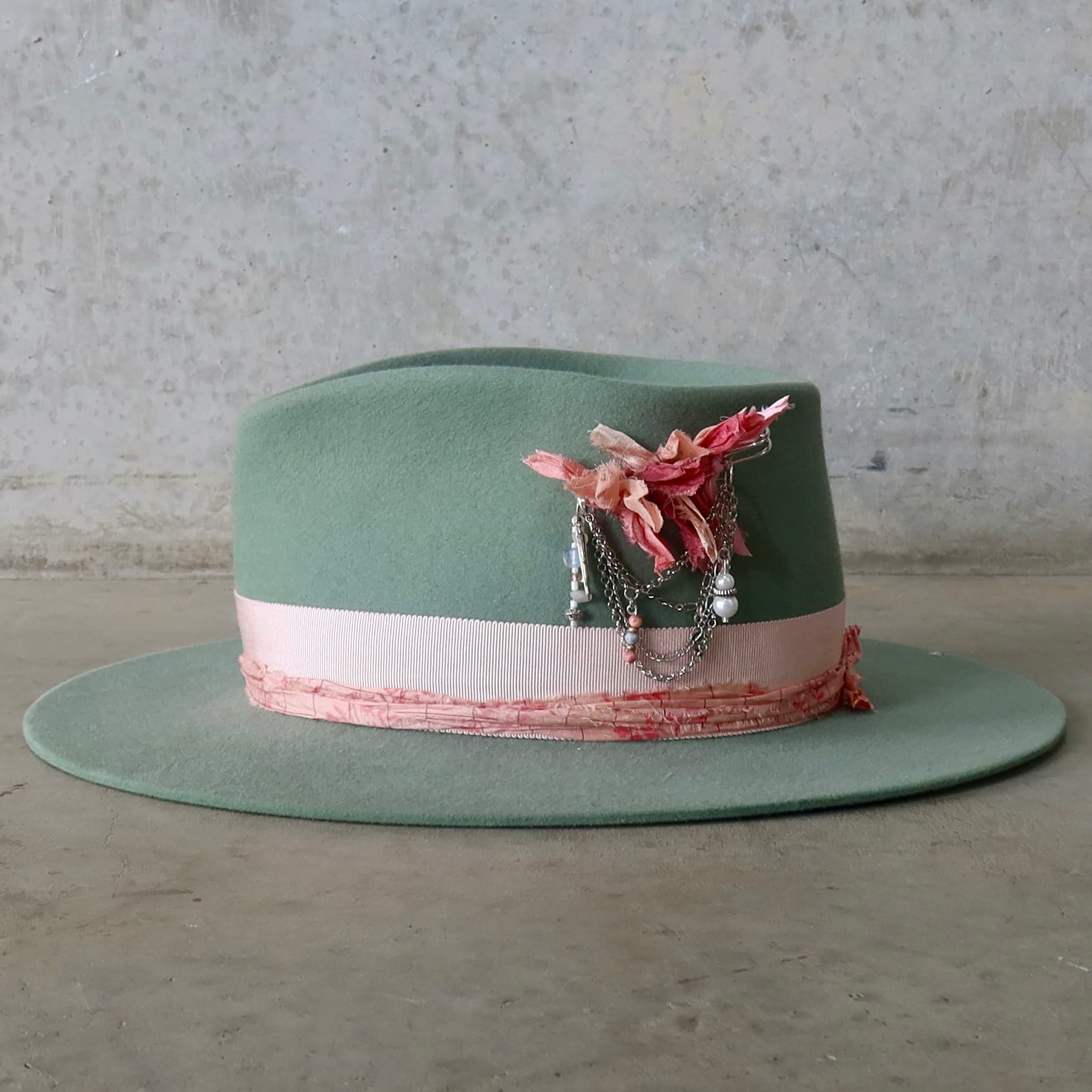 Left side view of the Eucalyptus felt hat Diamonds & Pearls – Pink by PHYLLi Designs with Sherbet Pink Japanese grosgrain band and silver chunky hat pin trim.