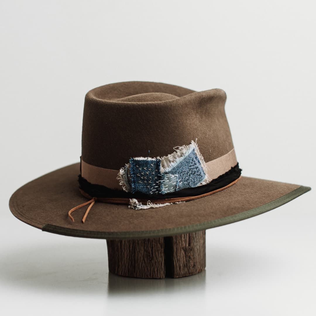 Back right angle of the Dirty Jane dirty olive felt hat by PHYLLi Designs featuring the Wabi Sabi denim and linen patch with visible hand stitching.