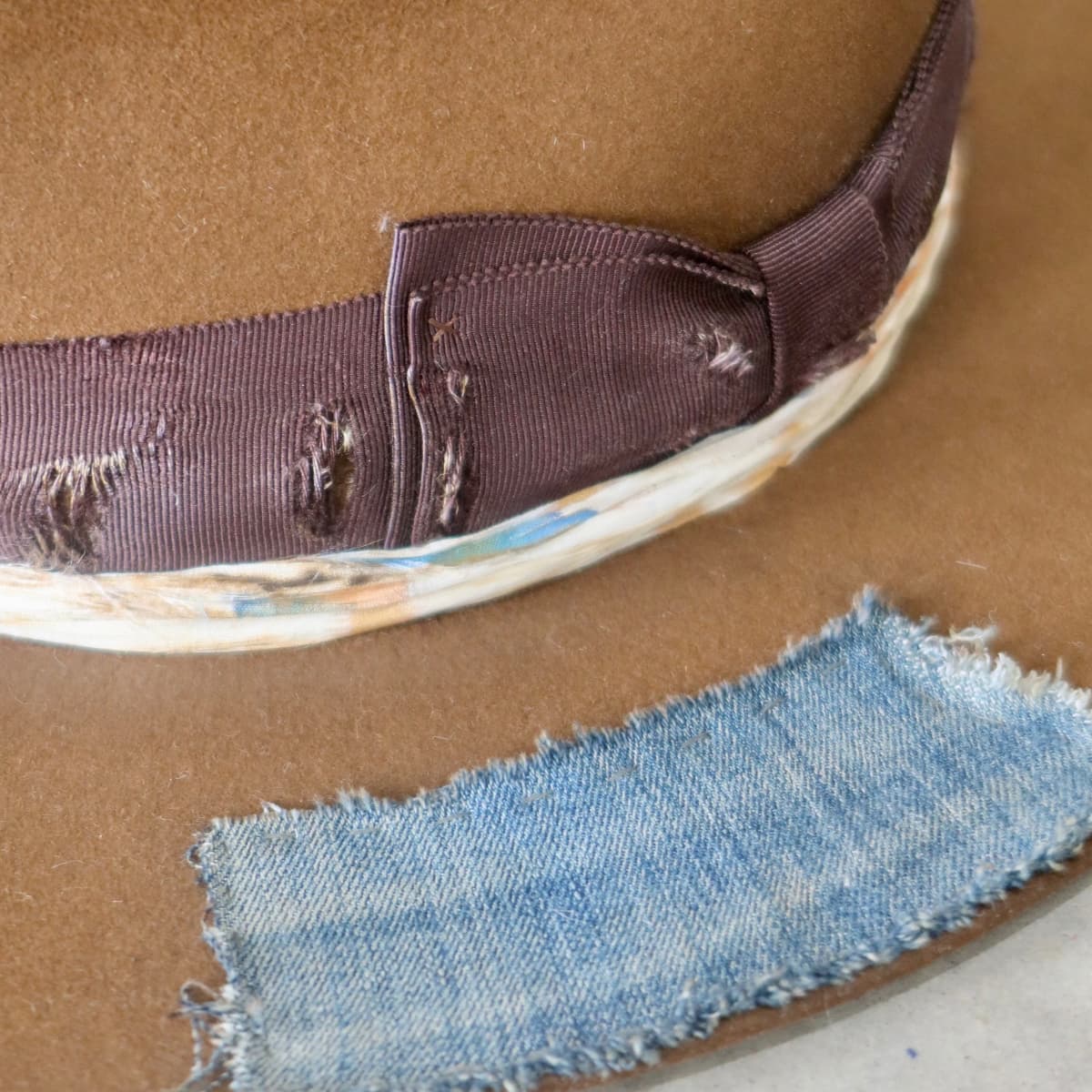 Close up detail of the Duke Limited Edition felt hat showing distressed chocolate grosgrain band and sari silk trimming.