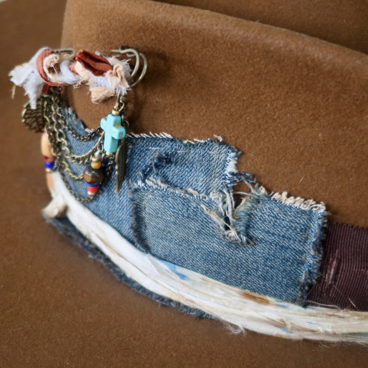 Close up detail of the Duke Limited Edition felt hat showing distressed denim patch trim and sari silk layers.