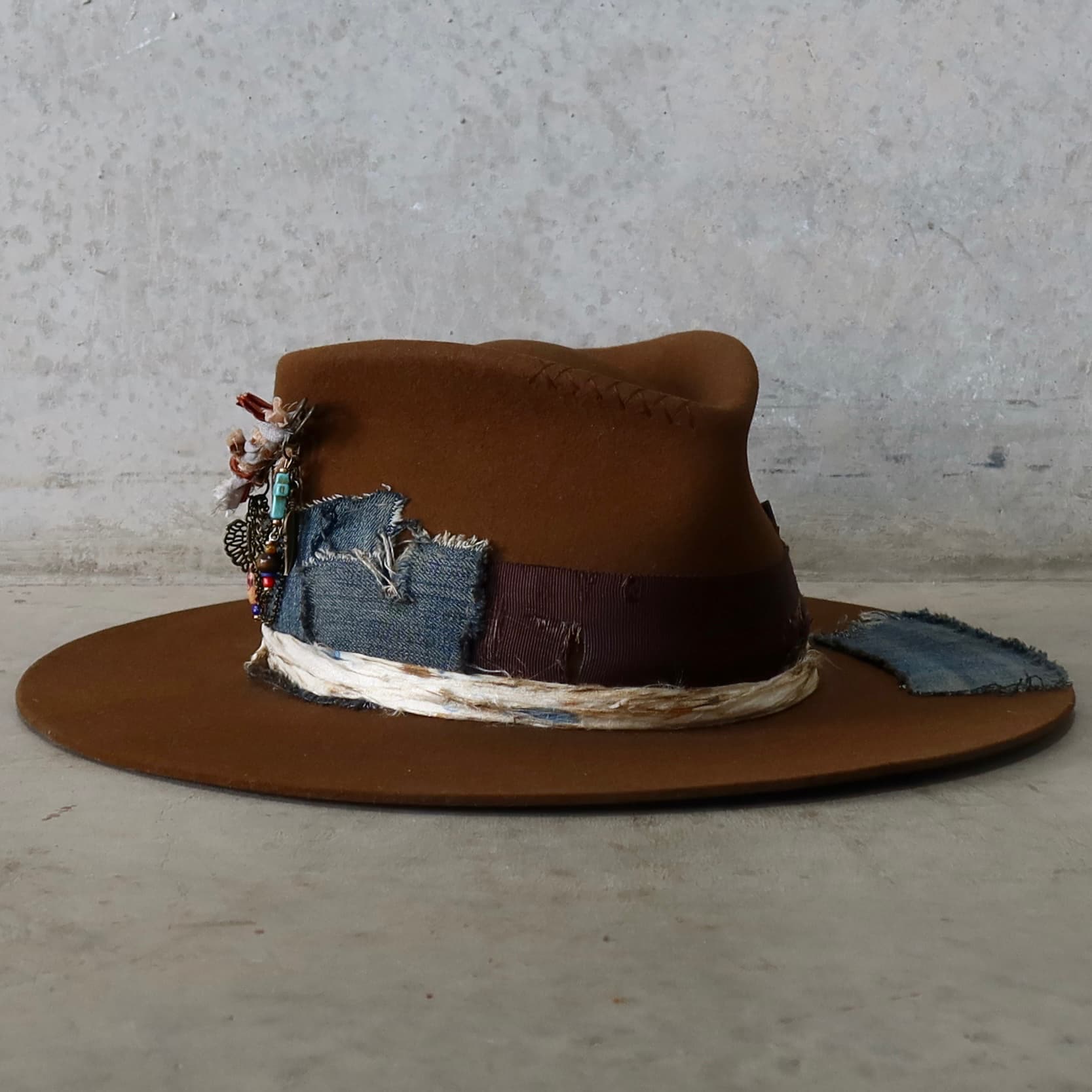 Front right angle of the caramel felt hat Duke Limited Edition by PHYLLi Designs featuring distressed denim patches and hand-stitched crosses.