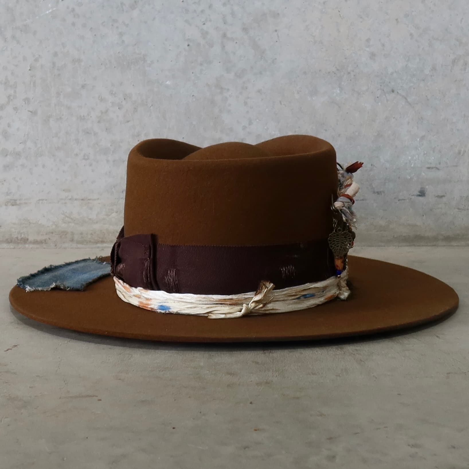 Back view of the caramel felt hat Duke Limited Edition by PHYLLi Designs featuring denim patch trims and sari silk layering.