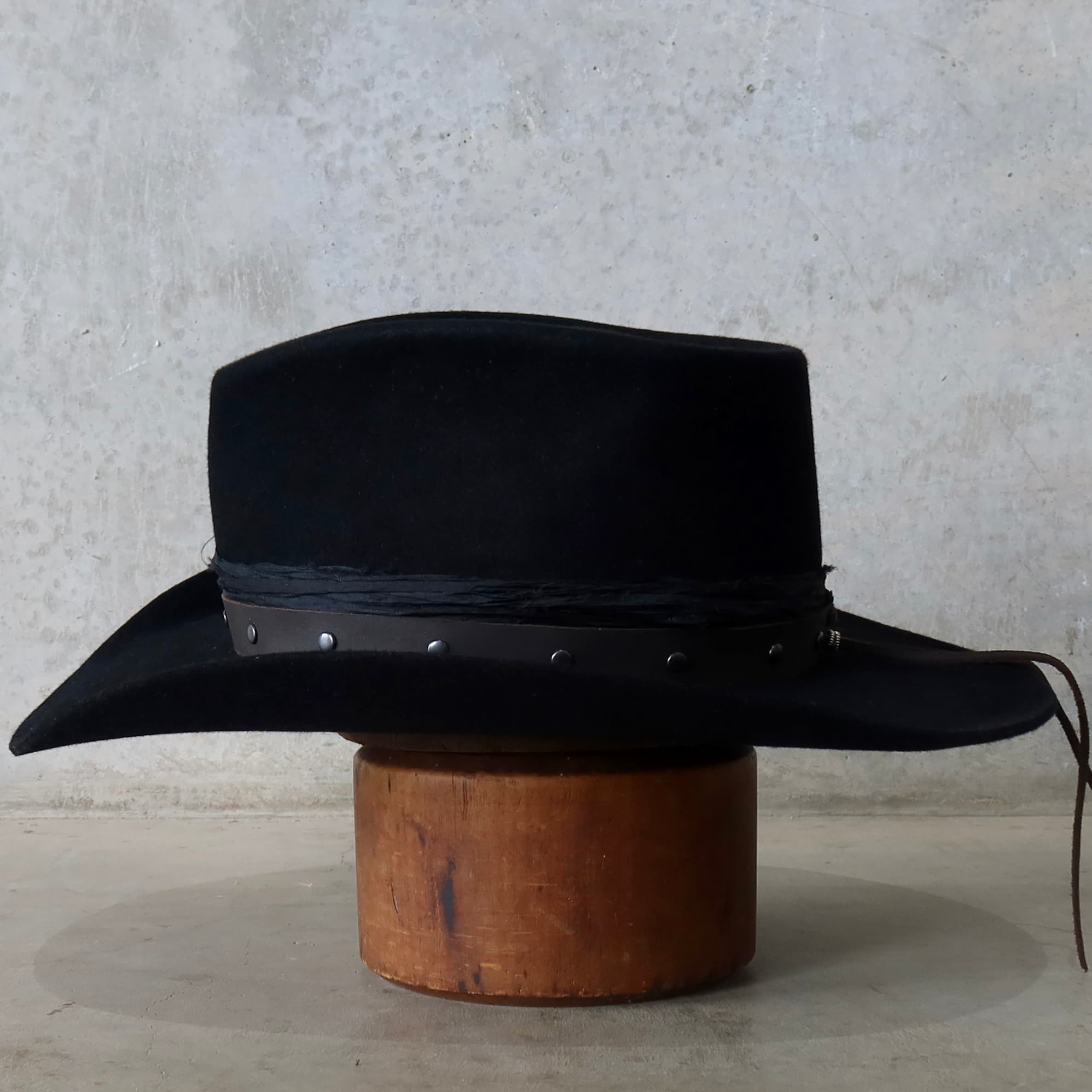 Left side view of the black felt cowboy hat Edwards by PHYLLi Designs with studded buffalo leather hat band.