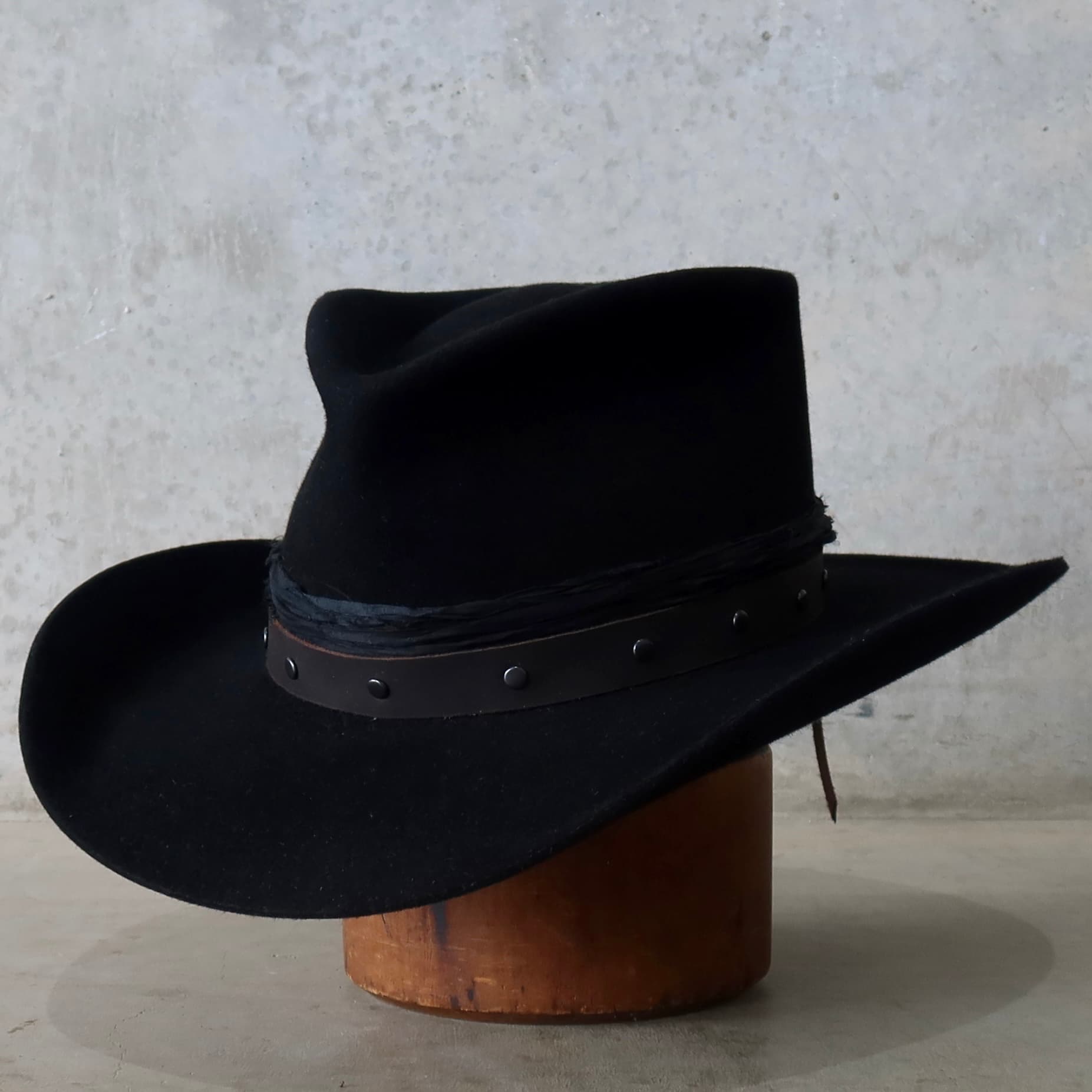 Front left angle of the black felt cowboy hat Edwards by PHYLLi Designs with studded buffalo leather band and sari silk trim.