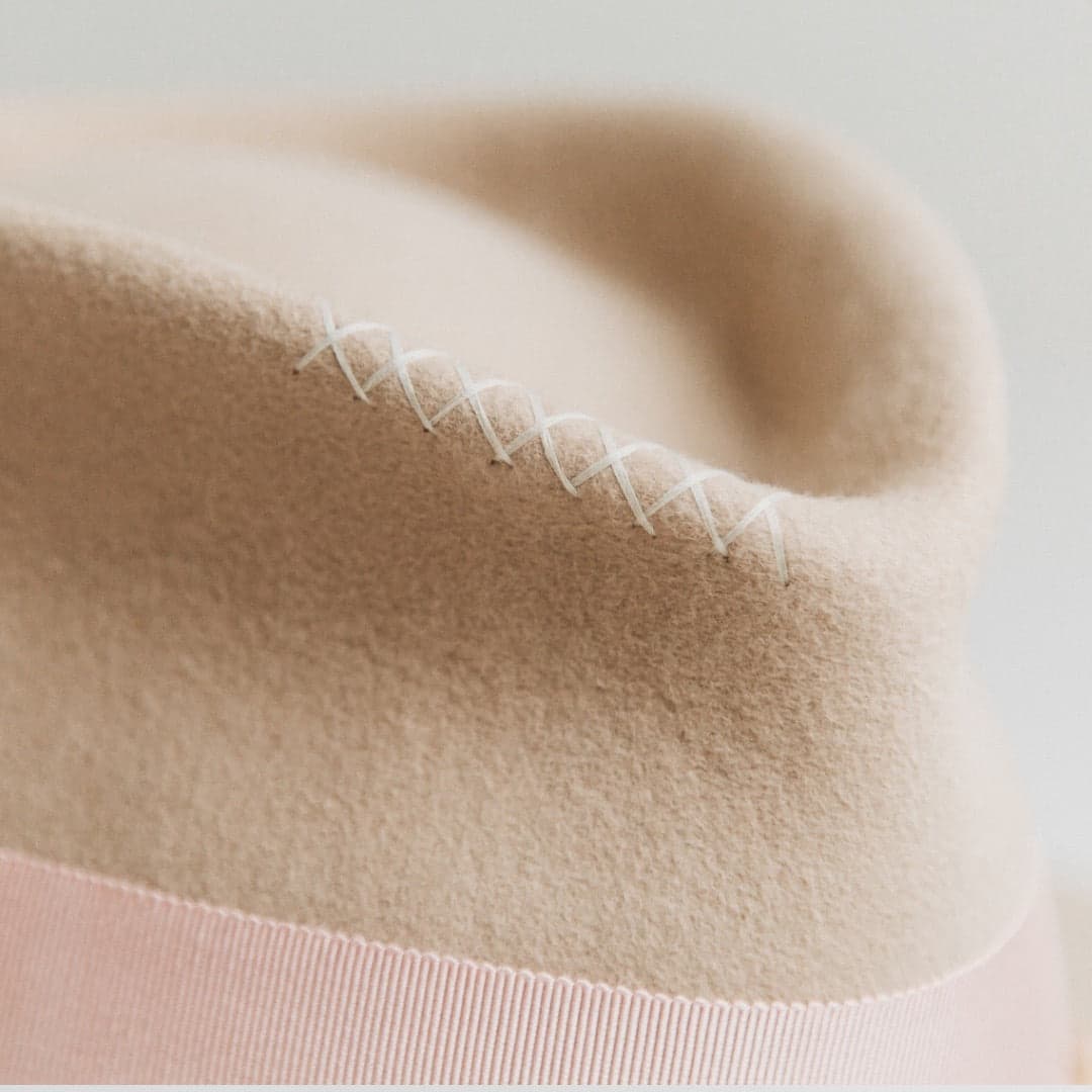 Close up detail of the Eleanor beige felt hat by PHYLLi Designs showing ivory hand-stitched crosses along the crown crease.
