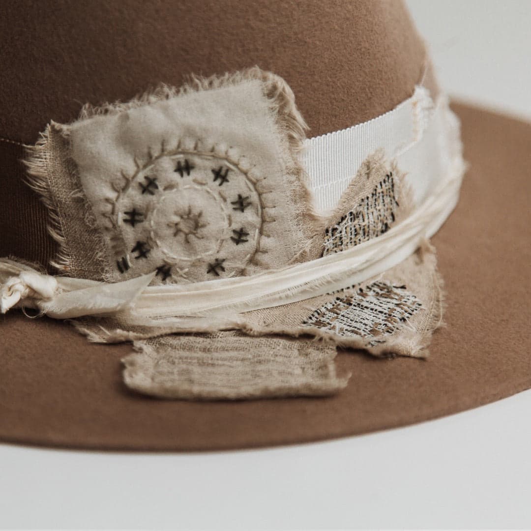 Close up detail of the Enso felt hat showing wabi sabi fabric patch with circular hand stitching.